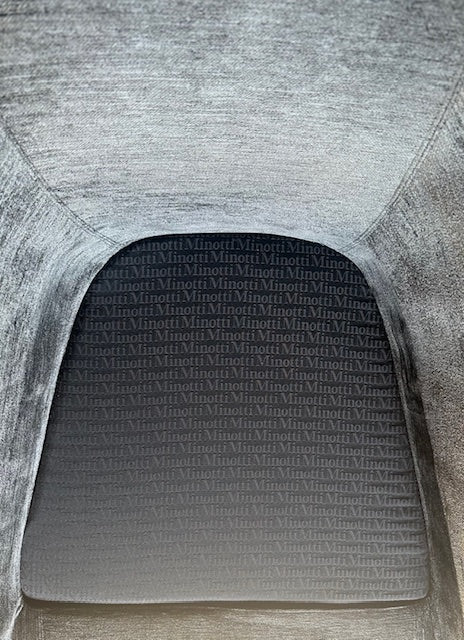 The Minotti Quinn Swivel Lounge Chair Set of 2 showcases a minimalist design with dark gray, curved forms in luxurious chenille. Ideal for the living room, these modern chairs stand out against a light gray backdrop.