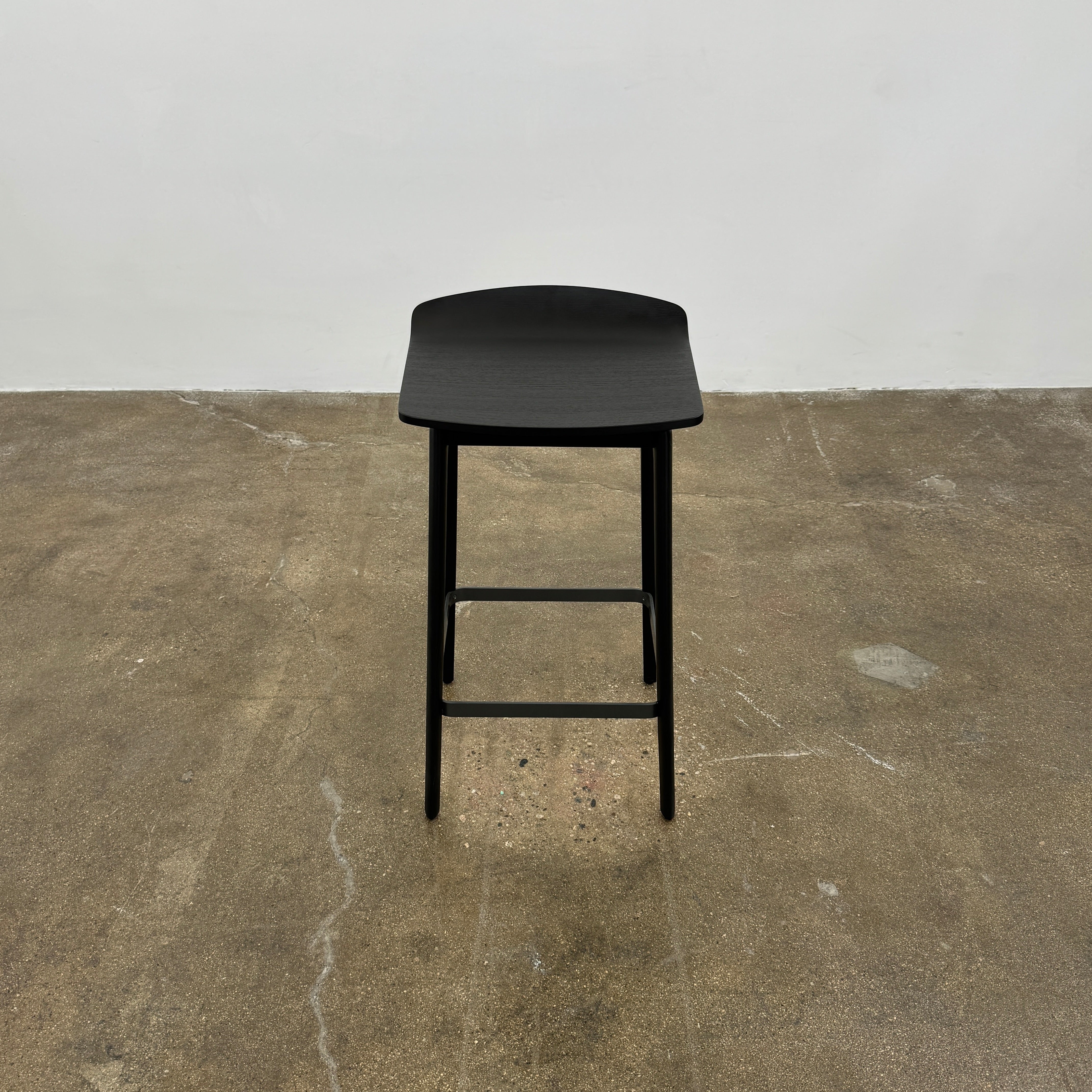 The Molteni & C Woody Kitchen Stool Set of 2 features black solid ash wood stools with curved seats and four legs, joined by support bars, shown on a plain white background.