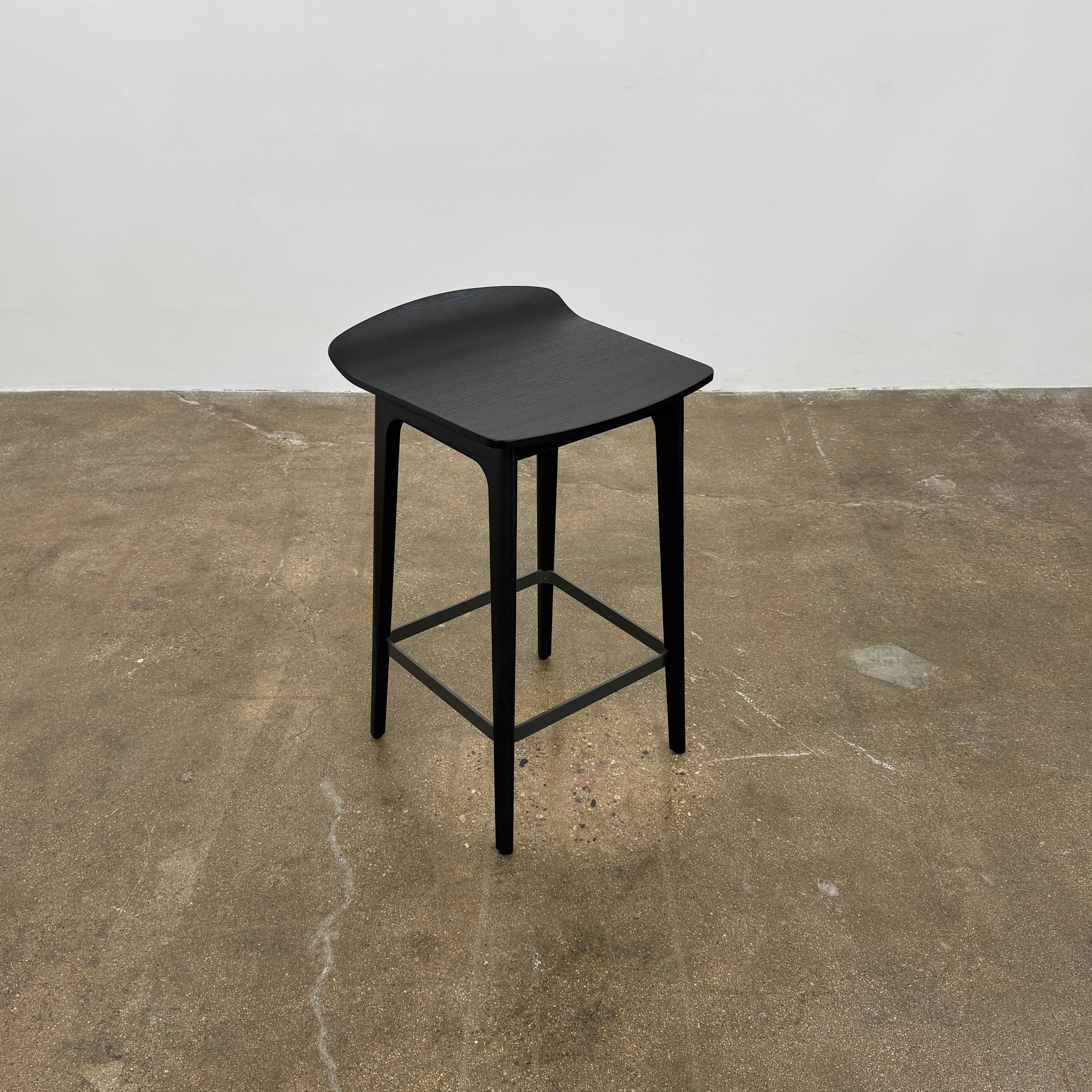 The Molteni & C Woody Kitchen Stool Set of 2 features black solid ash wood stools with curved seats and four legs, joined by support bars, shown on a plain white background.