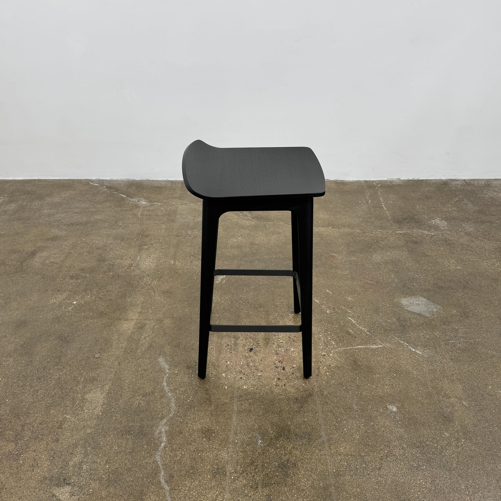 The Molteni & C Woody Kitchen Stool Set of 2 features black solid ash wood stools with curved seats and four legs, joined by support bars, shown on a plain white background.