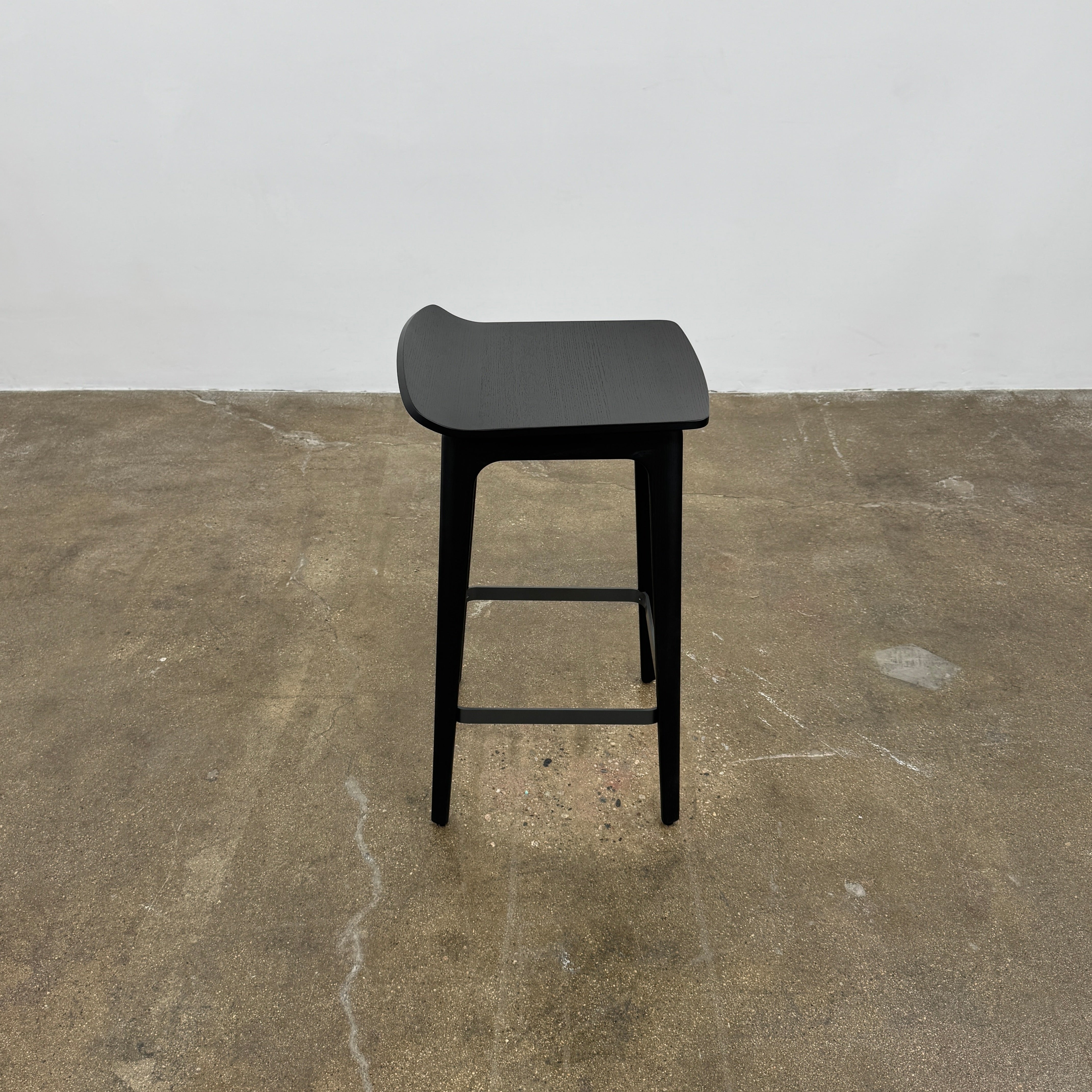 The Molteni & C Woody Kitchen Stool Set of 2 features black solid ash wood stools with curved seats and four legs, joined by support bars, shown on a plain white background.