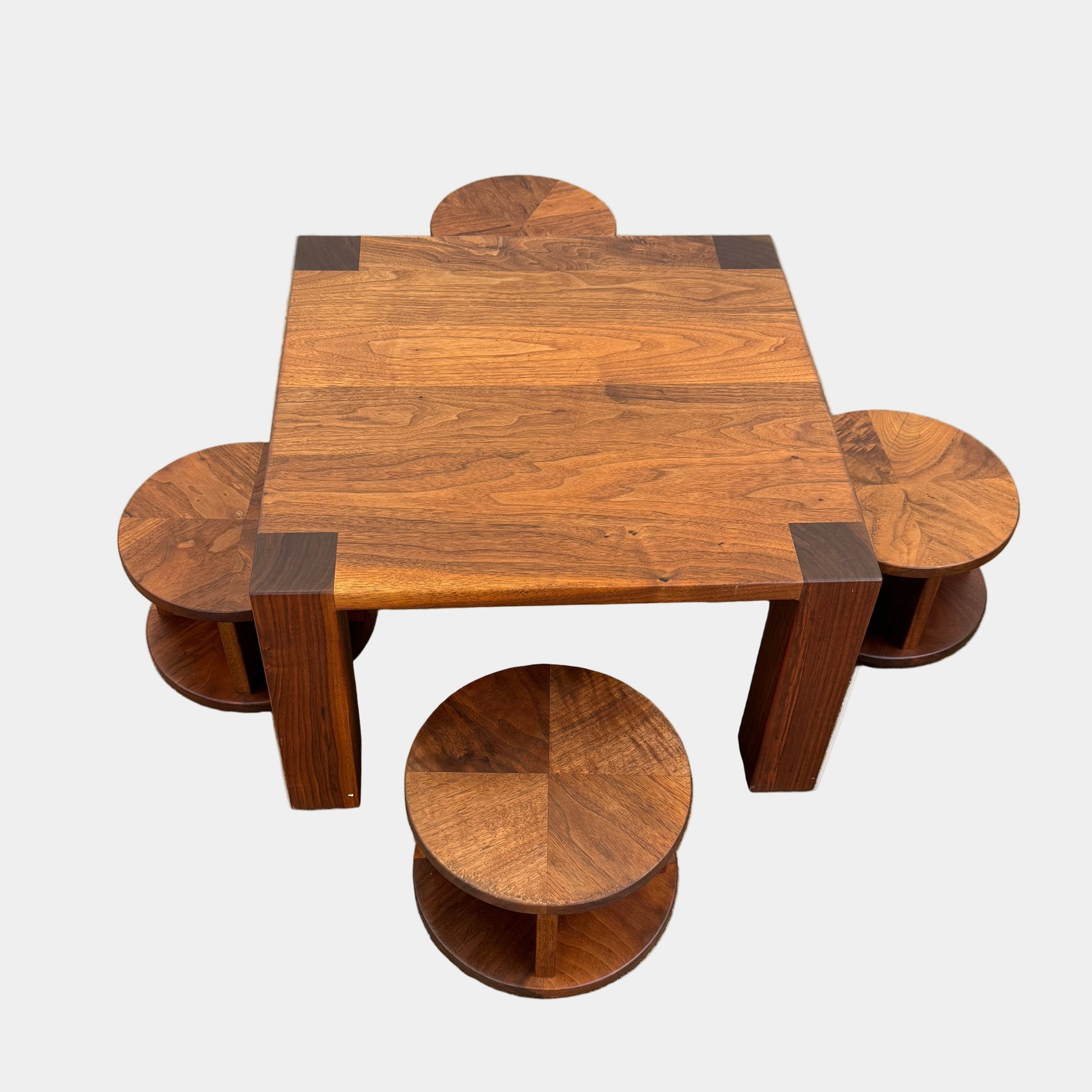 The Marmol Radziner Asher Children's Table and Stools features a square wooden table with four round stools fitting neatly underneath, all by Marmol Radziner, shown against a white background and inspired by their timeless design.