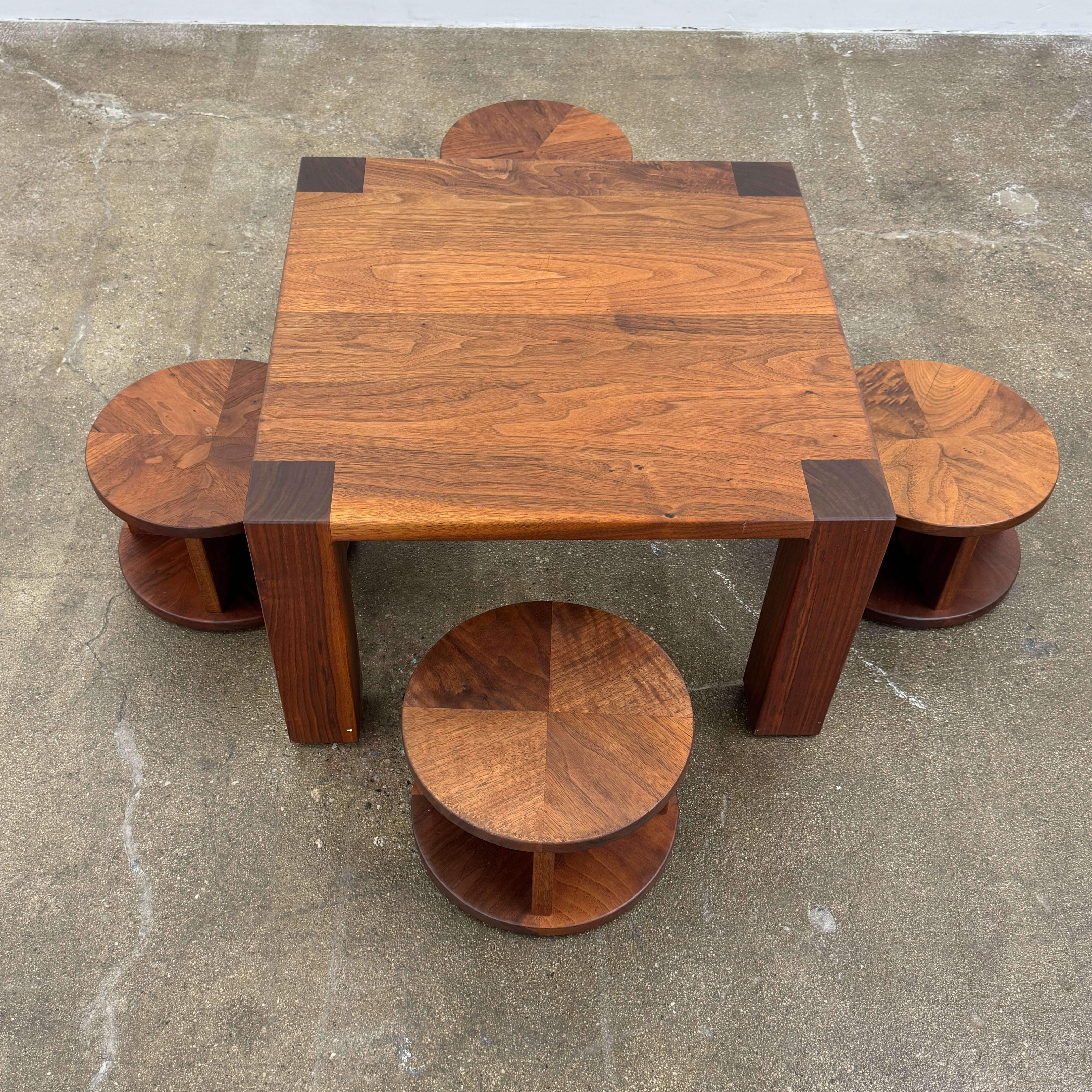 The Marmol Radziner Asher Children's Table and Stools features a square wooden table with four round stools fitting neatly underneath, all by Marmol Radziner, shown against a white background and inspired by their timeless design.