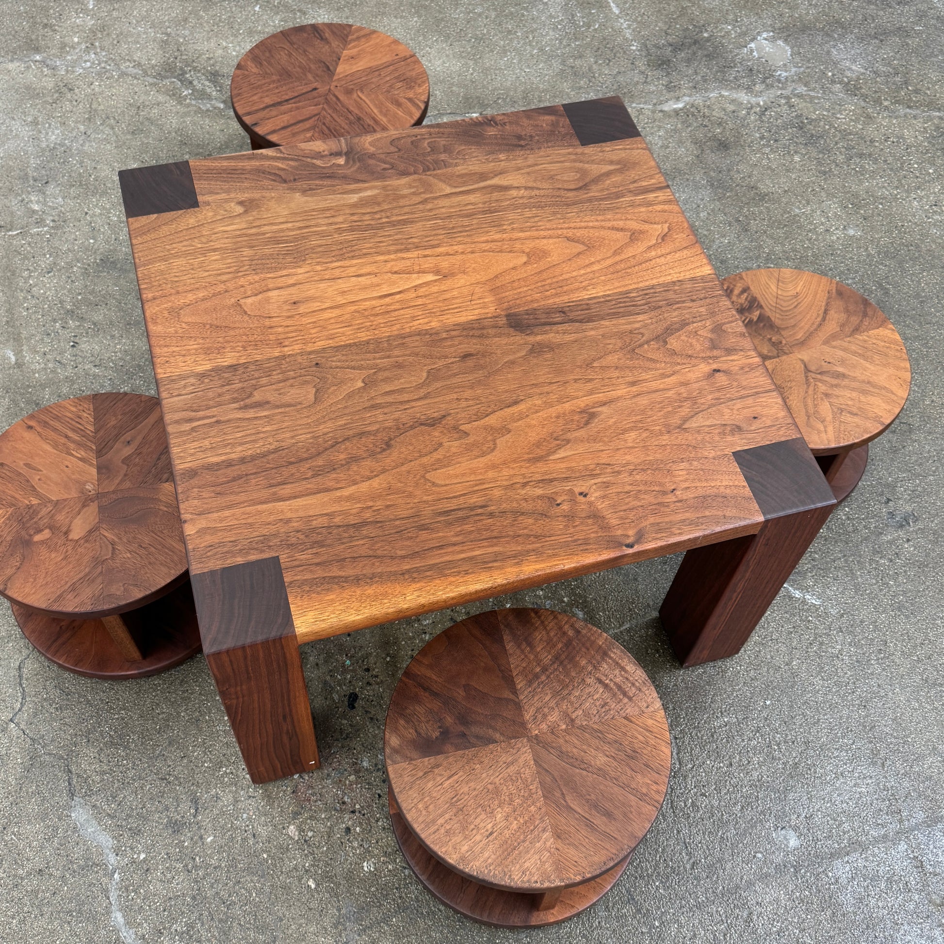 The Marmol Radziner Asher Children's Table and Stools features a square wooden table with four round stools fitting neatly underneath, all by Marmol Radziner, shown against a white background and inspired by their timeless design.