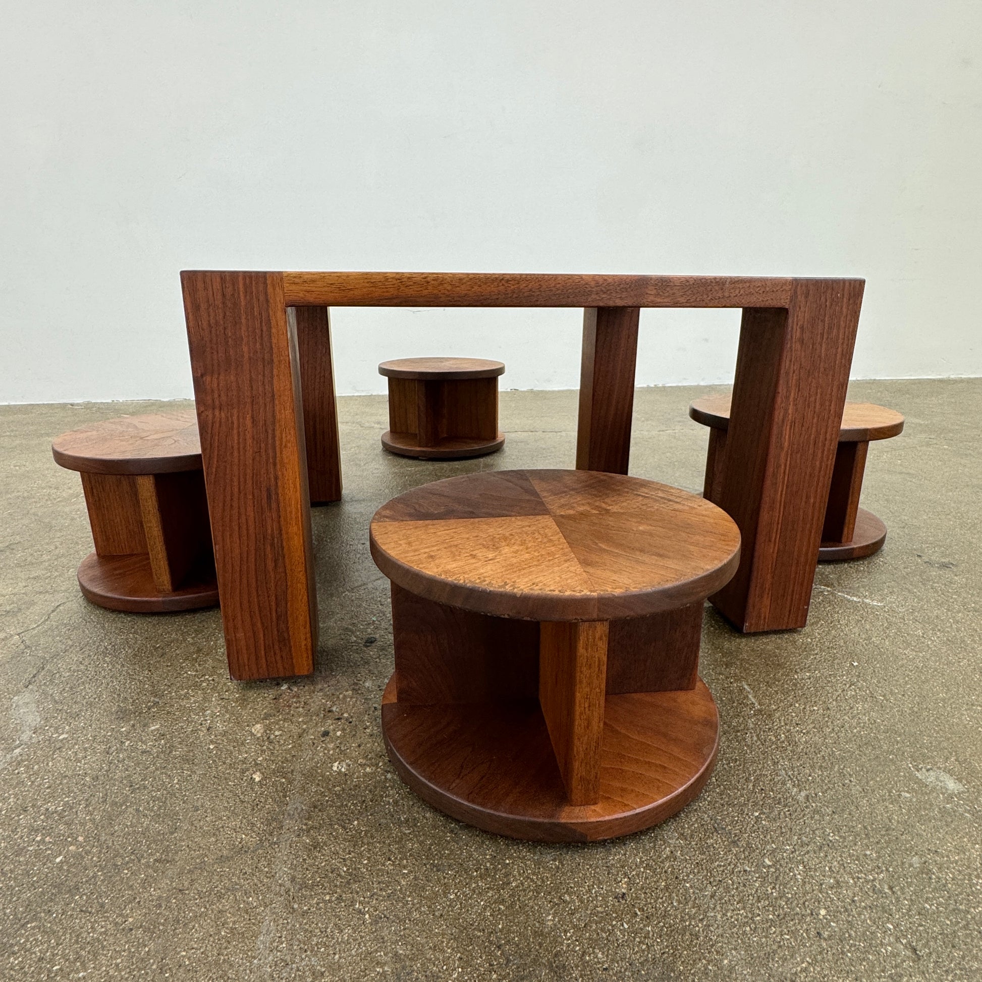 The Marmol Radziner Asher Children's Table and Stools features a square wooden table with four round stools fitting neatly underneath, all by Marmol Radziner, shown against a white background and inspired by their timeless design.