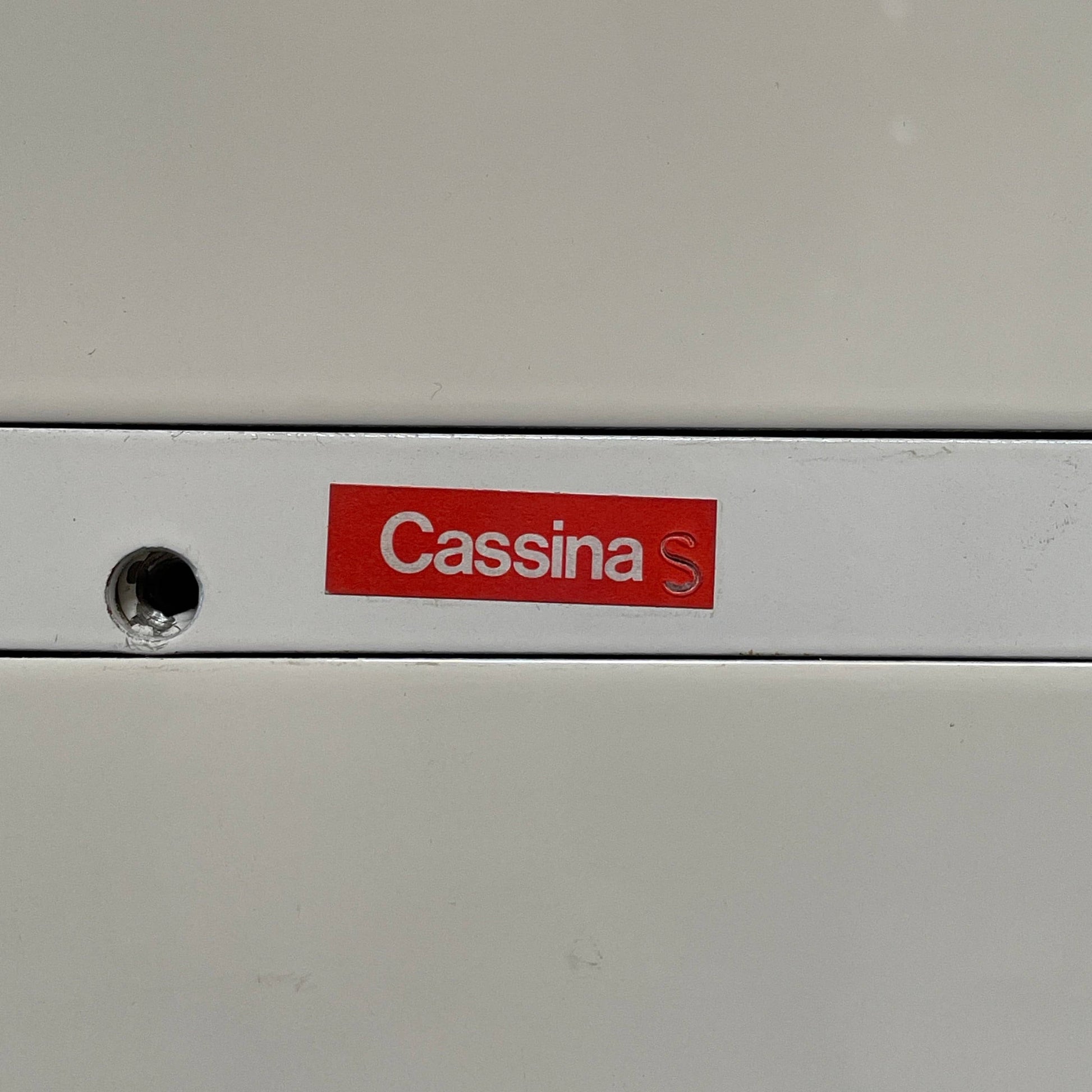 The Cassina 255-256 Flat Sideboard in glossy white lacquer features two left drawers, a spacious right compartment, and four metal legs, all by Cassina, shown against a plain background.