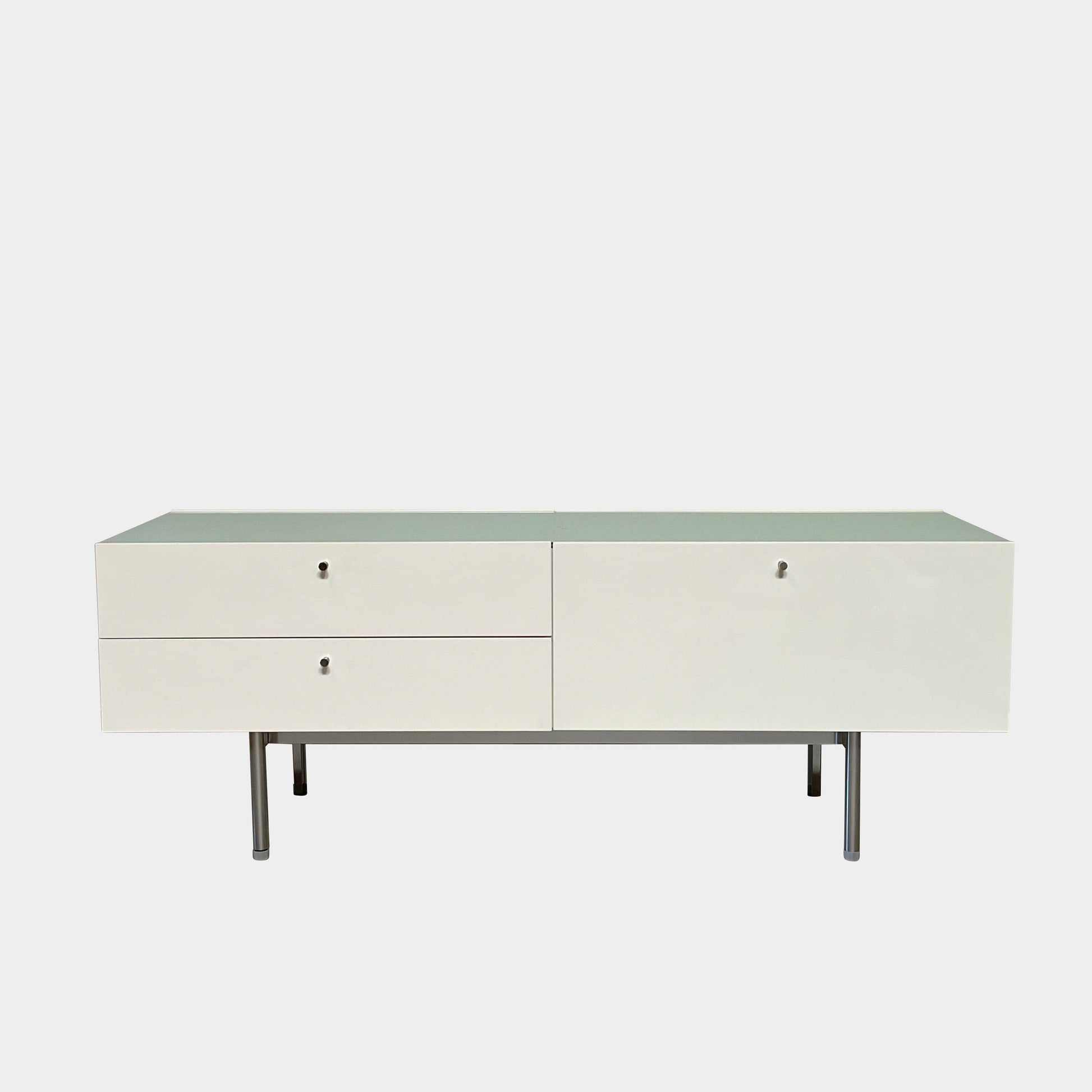 The Cassina 255-256 Flat Sideboard in glossy white lacquer features two left drawers, a spacious right compartment, and four metal legs, all by Cassina, shown against a plain background.