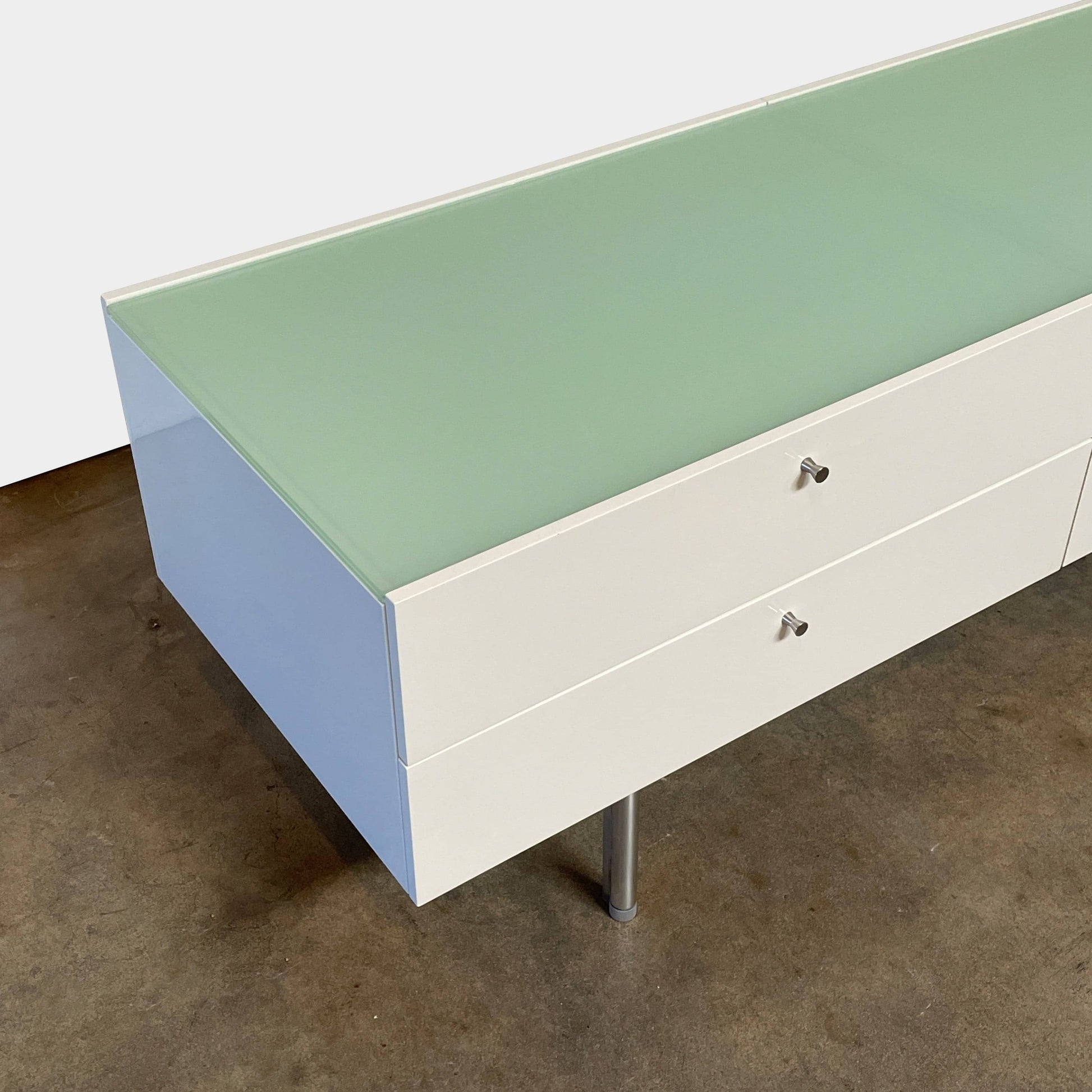 The Cassina 255-256 Flat Sideboard in glossy white lacquer features two left drawers, a spacious right compartment, and four metal legs, all by Cassina, shown against a plain background.