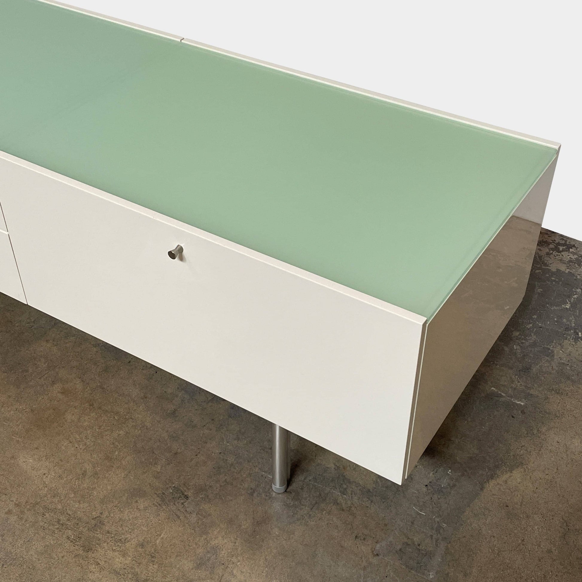 The Cassina 255-256 Flat Sideboard in glossy white lacquer features two left drawers, a spacious right compartment, and four metal legs, all by Cassina, shown against a plain background.