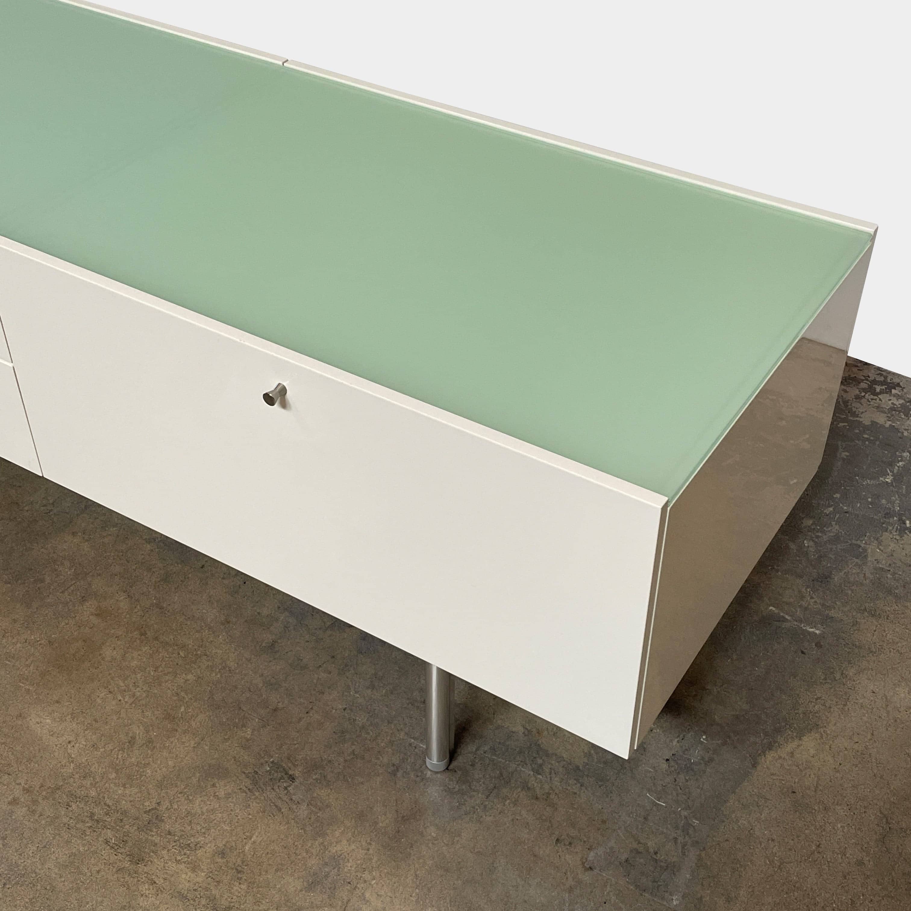 The Cassina 255-256 Flat Sideboard in glossy white lacquer features two left drawers, a spacious right compartment, and four metal legs, all by Cassina, shown against a plain background.