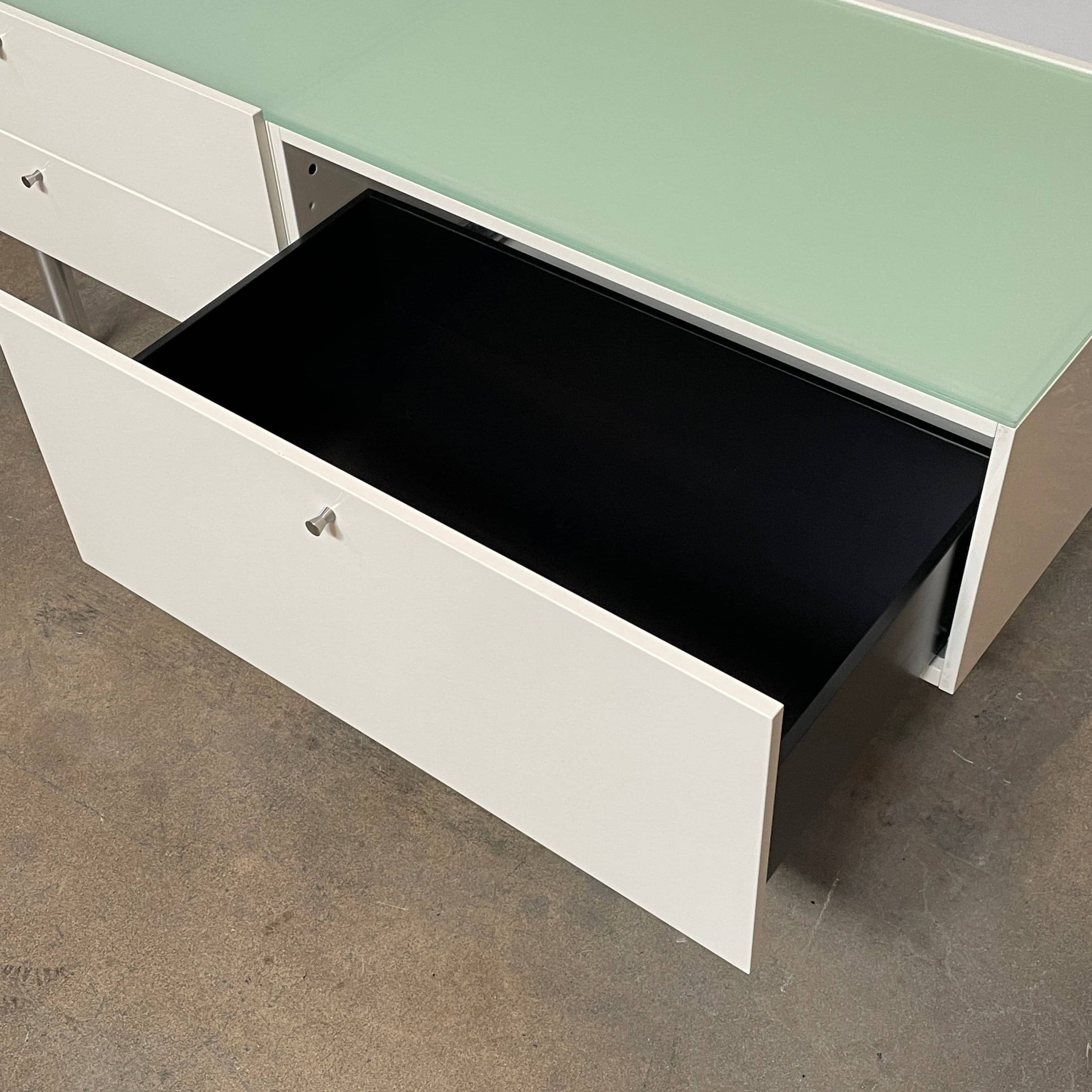 The Cassina 255-256 Flat Sideboard in glossy white lacquer features two left drawers, a spacious right compartment, and four metal legs, all by Cassina, shown against a plain background.