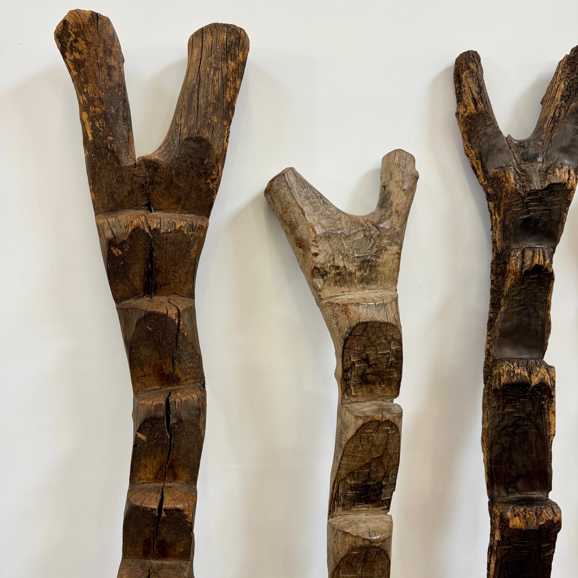 Four Vintage African Dogan Ladders, sold separately, feature wooden sticks with forked tops arranged vertically against a plain white background, showcasing distinctive African craftsmanship.