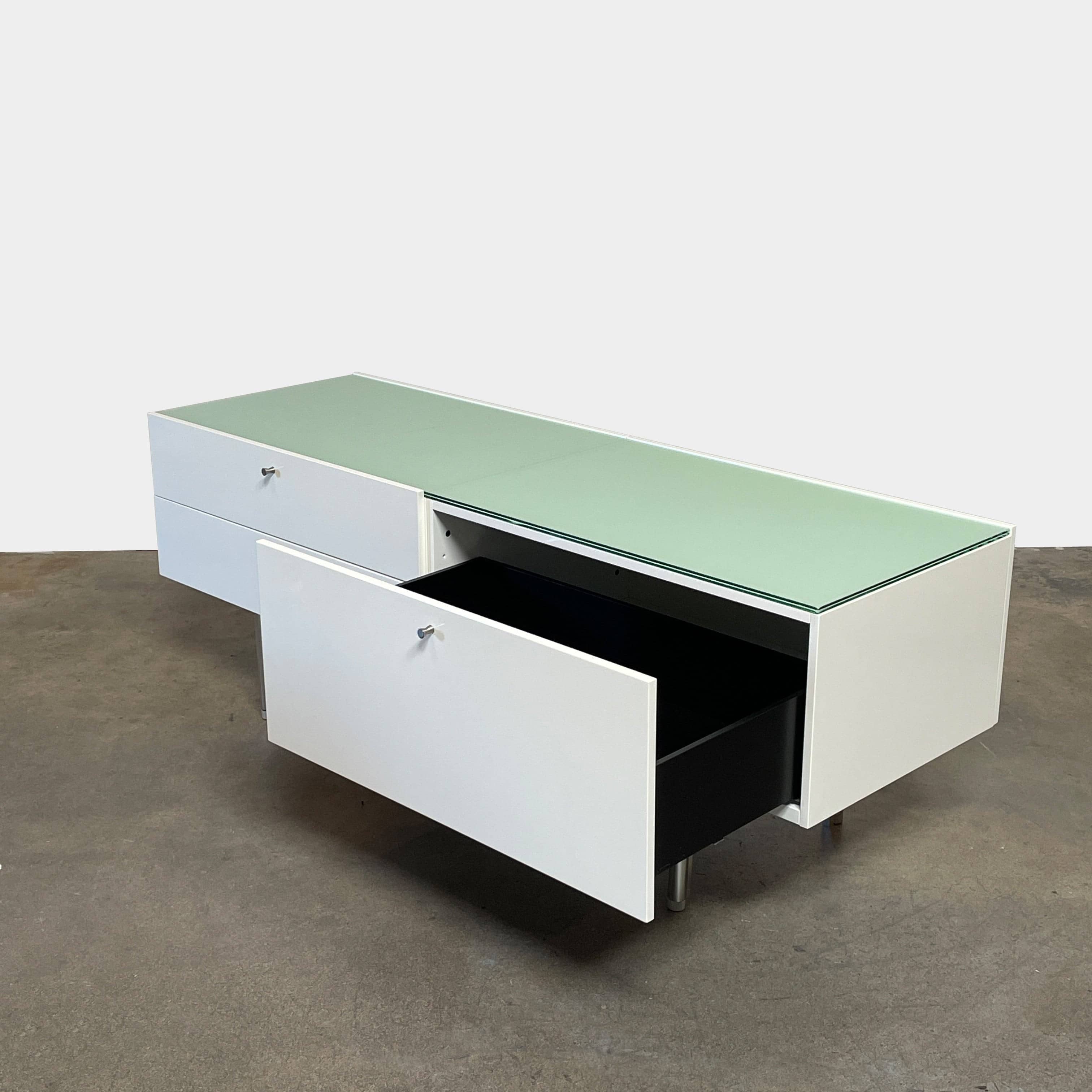The Cassina 255-256 Flat Sideboard in glossy white lacquer features two left drawers, a spacious right compartment, and four metal legs, all by Cassina, shown against a plain background.
