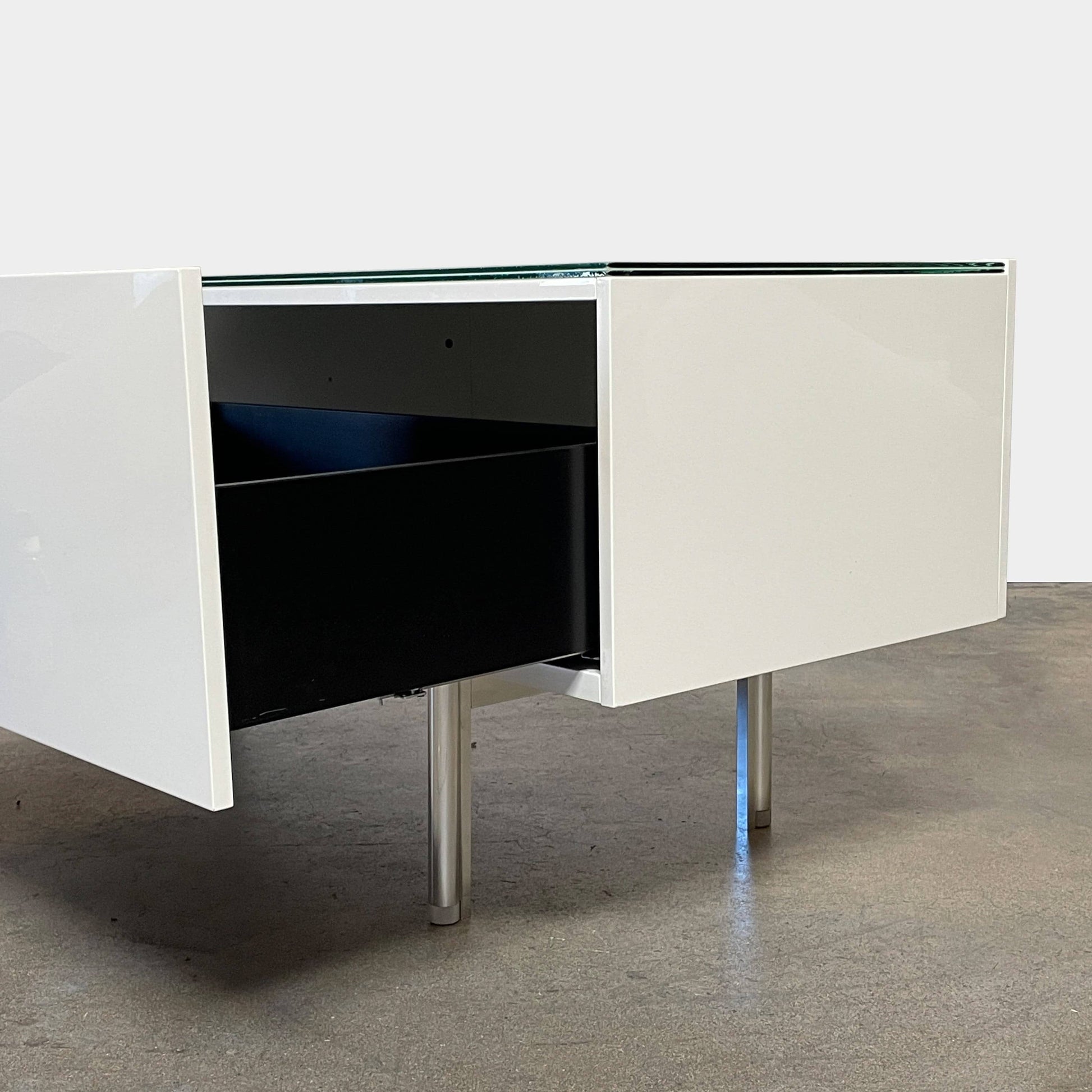 The Cassina 255-256 Flat Sideboard in glossy white lacquer features two left drawers, a spacious right compartment, and four metal legs, all by Cassina, shown against a plain background.