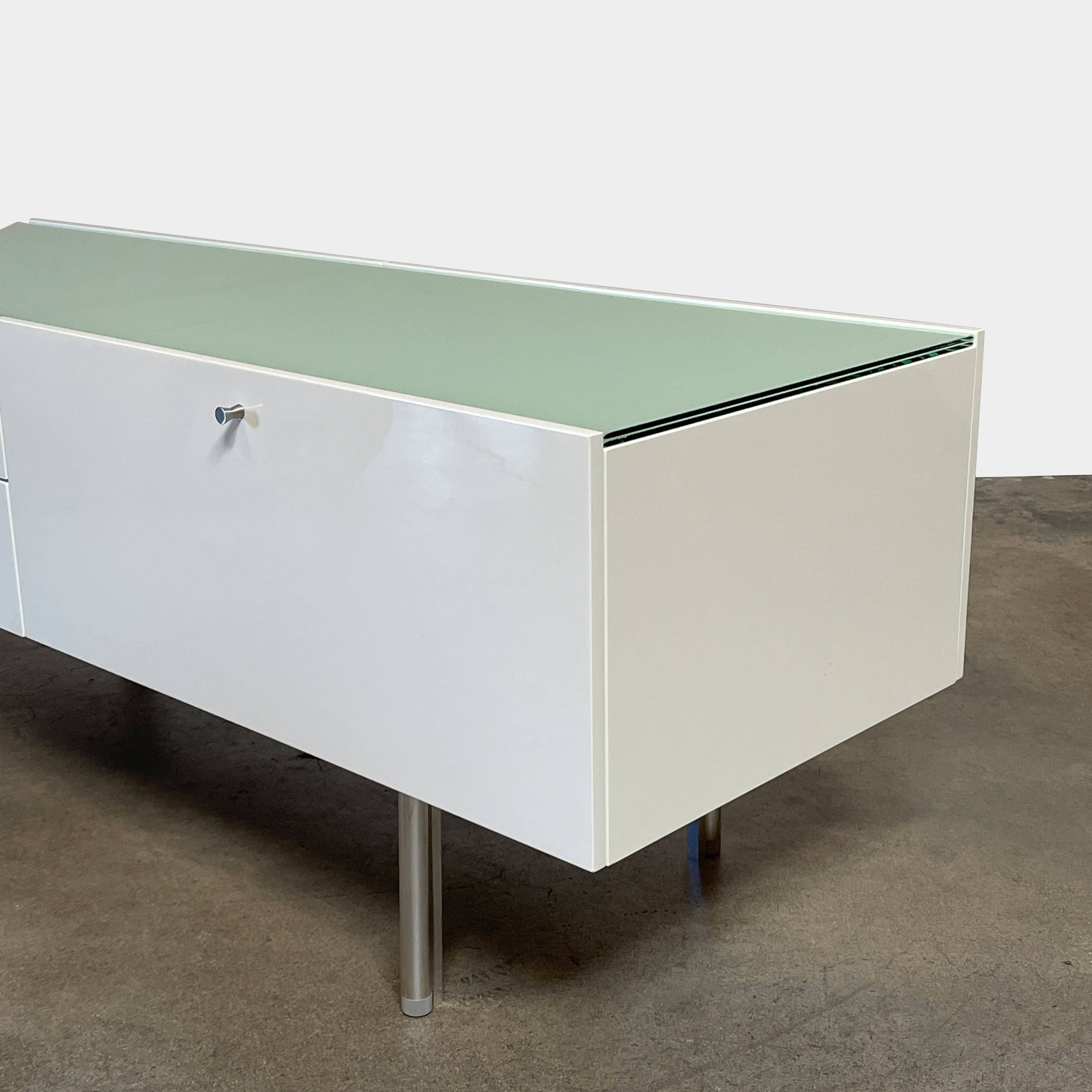 The Cassina 255-256 Flat Sideboard in glossy white lacquer features two left drawers, a spacious right compartment, and four metal legs, all by Cassina, shown against a plain background.