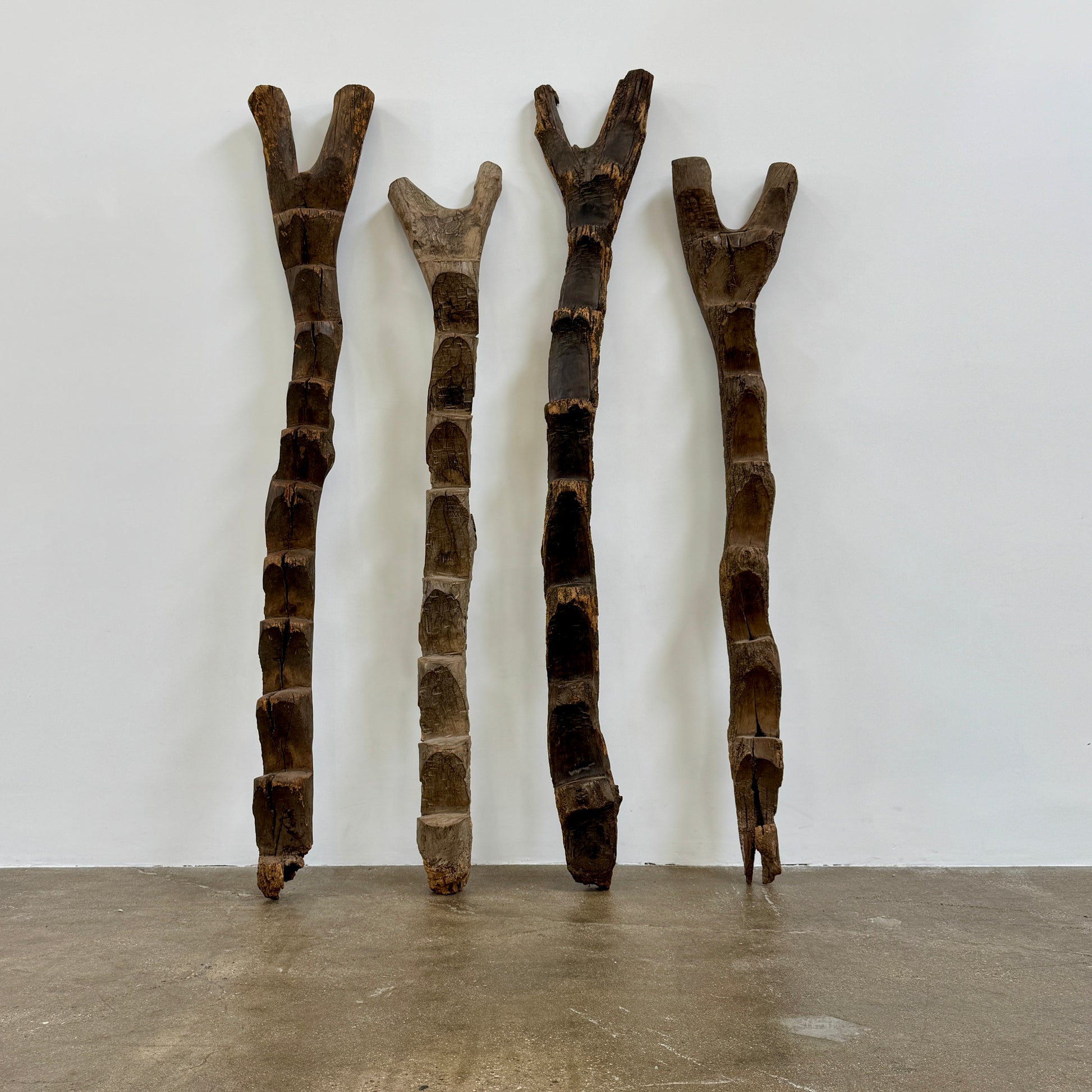 Four Vintage African Dogan Ladders, sold separately, feature wooden sticks with forked tops arranged vertically against a plain white background, showcasing distinctive African craftsmanship.