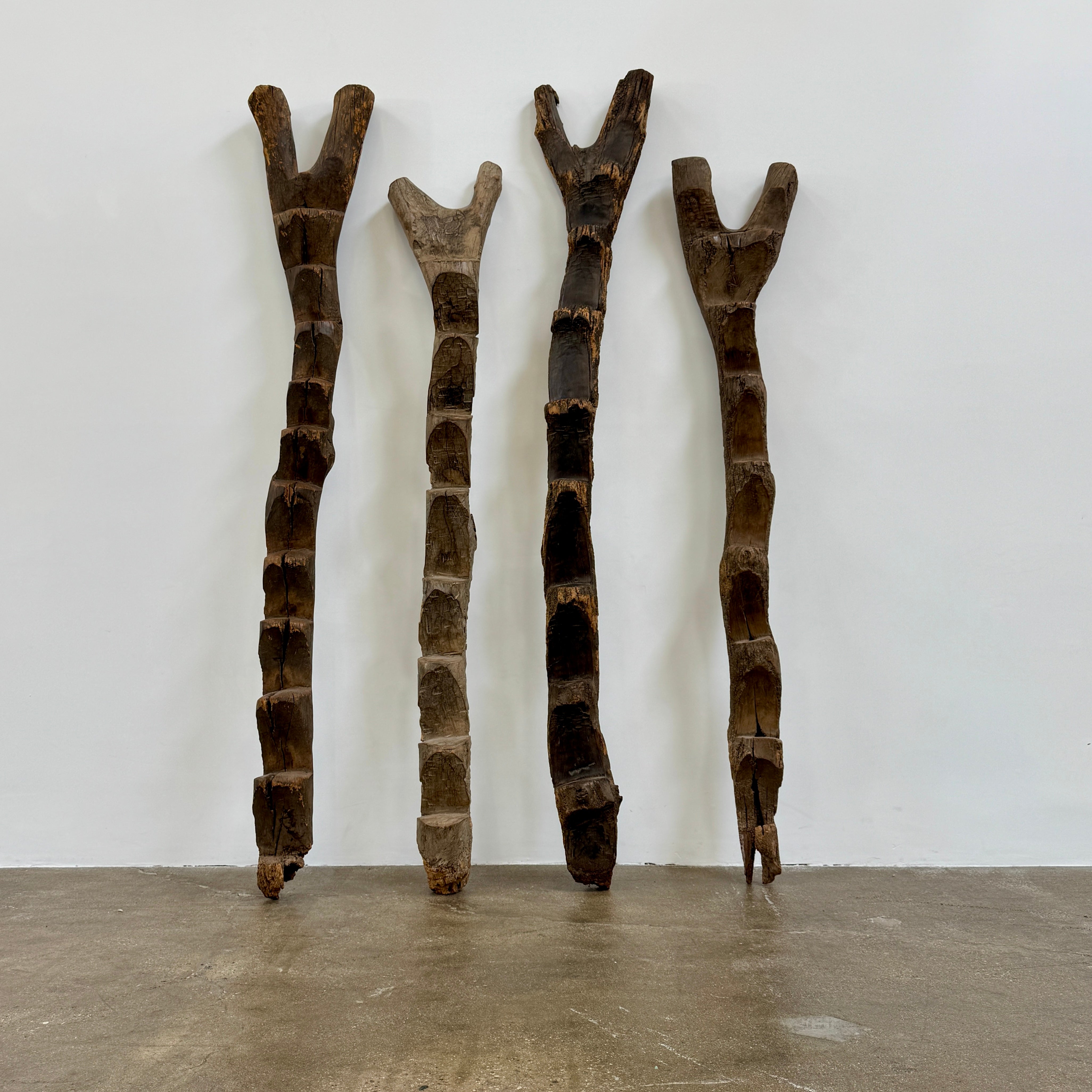 Four Vintage African Dogan Ladders, sold separately, feature wooden sticks with forked tops arranged vertically against a plain white background, showcasing distinctive African craftsmanship.