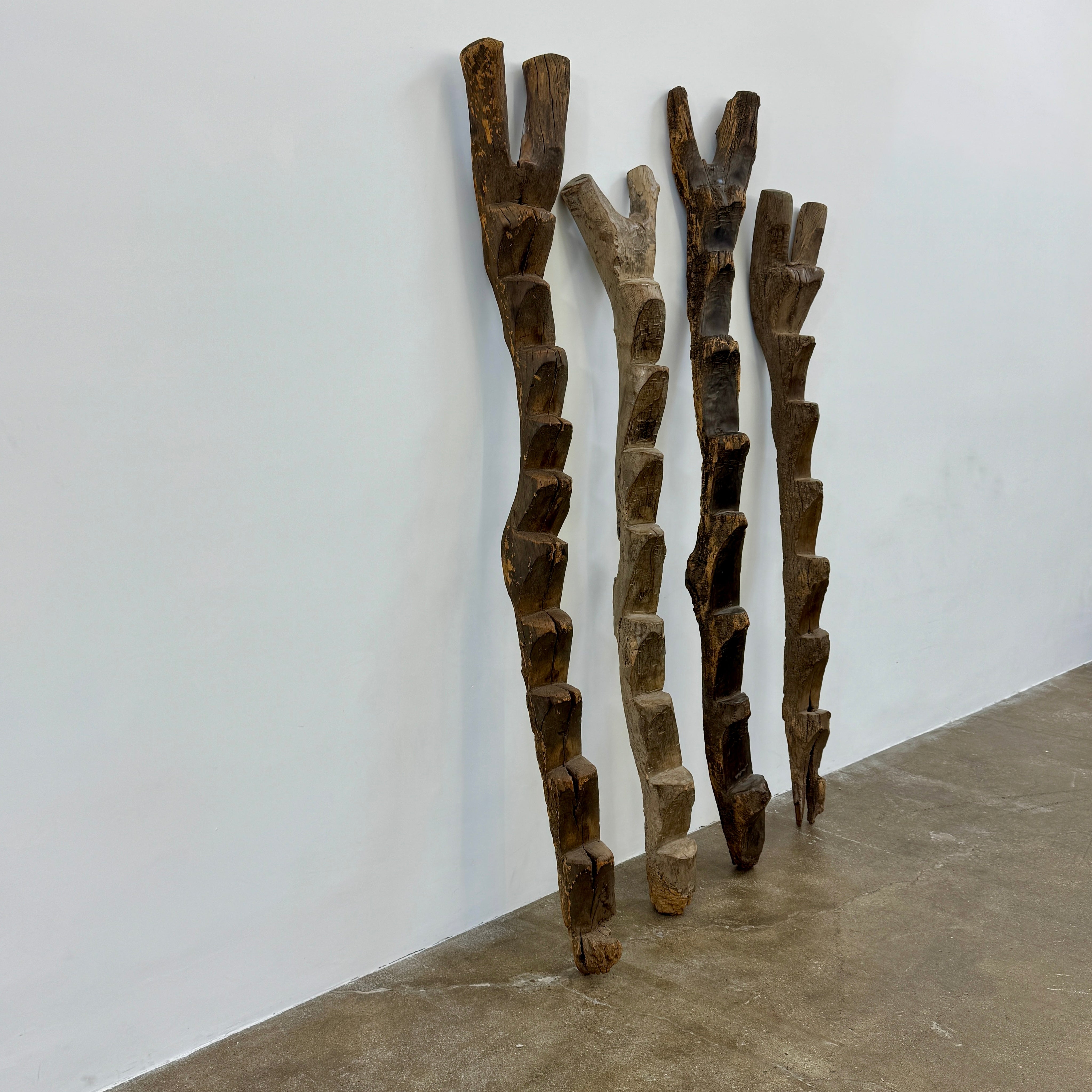 Four Vintage African Dogan Ladders, sold separately, feature wooden sticks with forked tops arranged vertically against a plain white background, showcasing distinctive African craftsmanship.