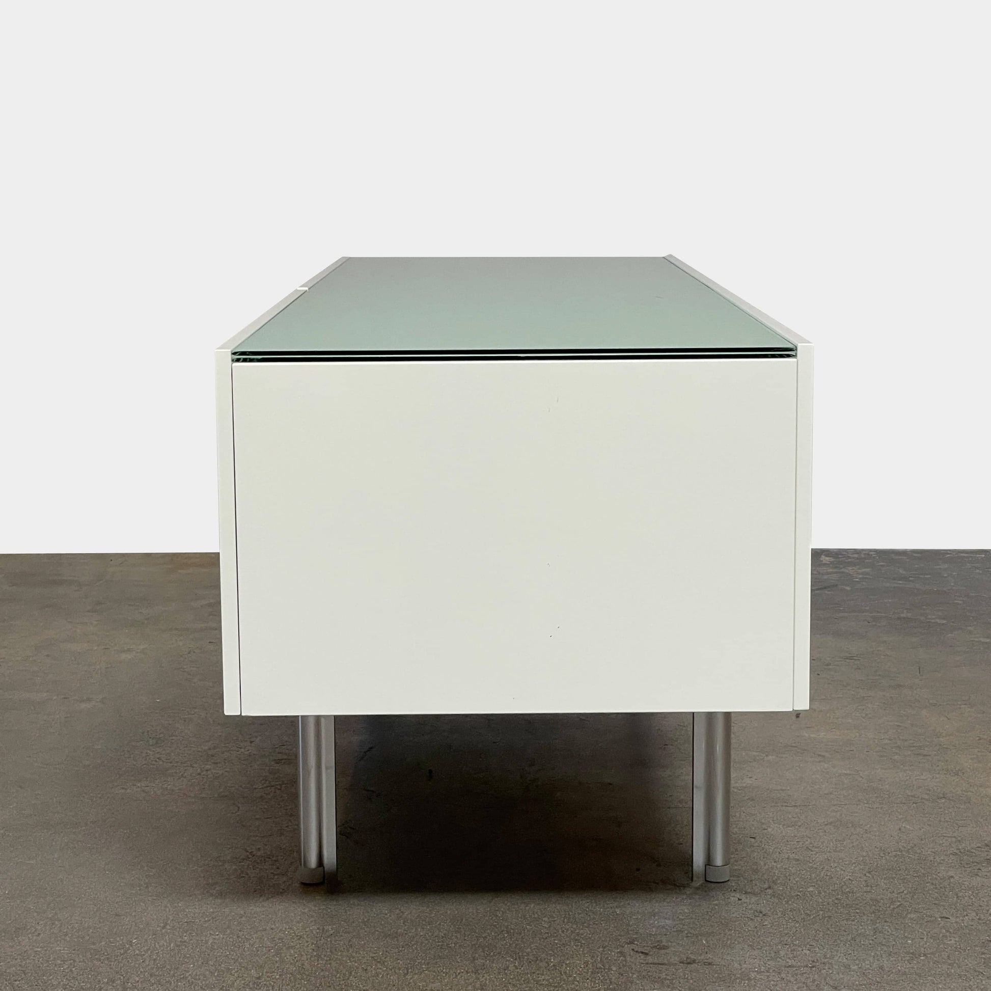 The Cassina 255-256 Flat Sideboard in glossy white lacquer features two left drawers, a spacious right compartment, and four metal legs, all by Cassina, shown against a plain background.