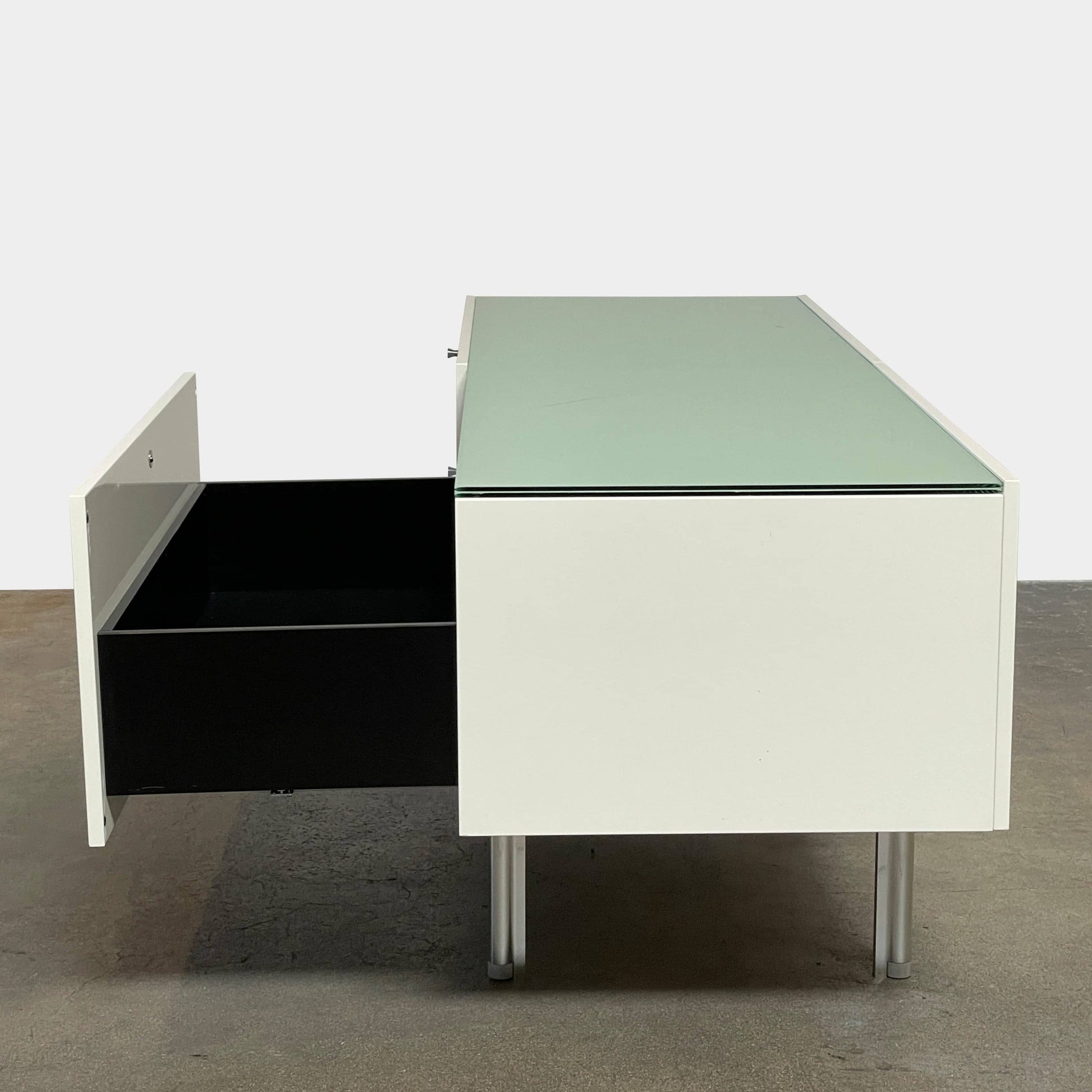 The Cassina 255-256 Flat Sideboard in glossy white lacquer features two left drawers, a spacious right compartment, and four metal legs, all by Cassina, shown against a plain background.