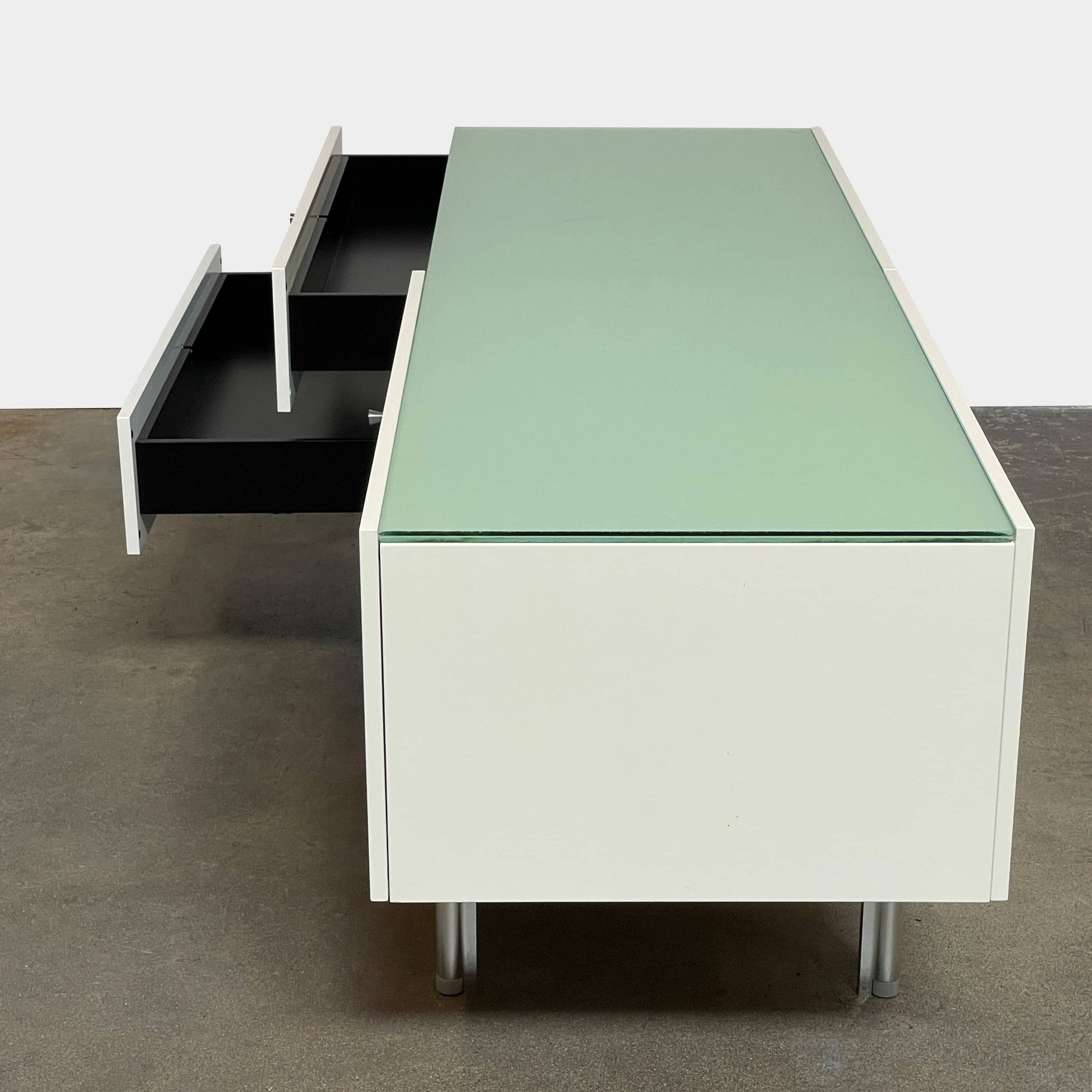 The Cassina 255-256 Flat Sideboard in glossy white lacquer features two left drawers, a spacious right compartment, and four metal legs, all by Cassina, shown against a plain background.