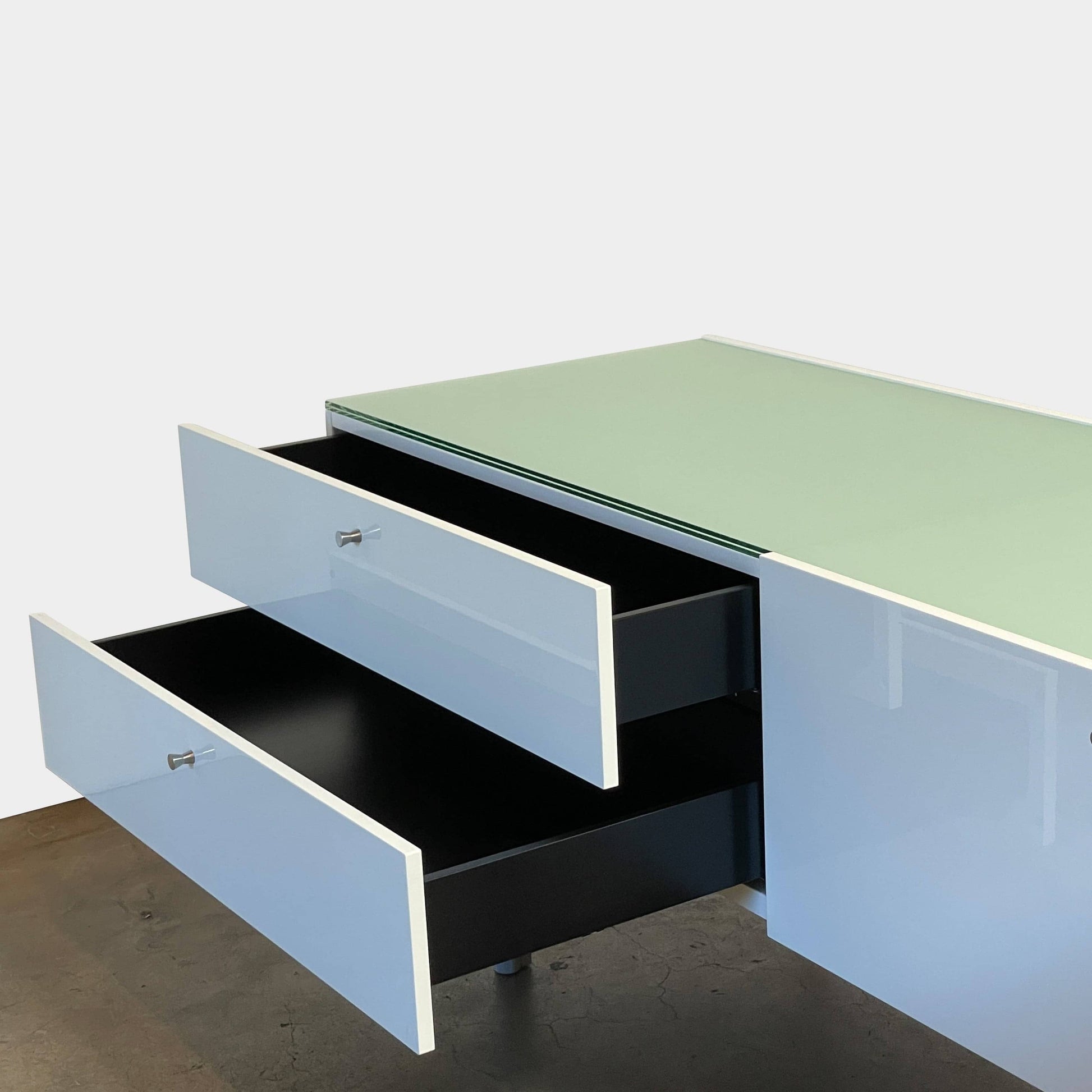 The Cassina 255-256 Flat Sideboard in glossy white lacquer features two left drawers, a spacious right compartment, and four metal legs, all by Cassina, shown against a plain background.