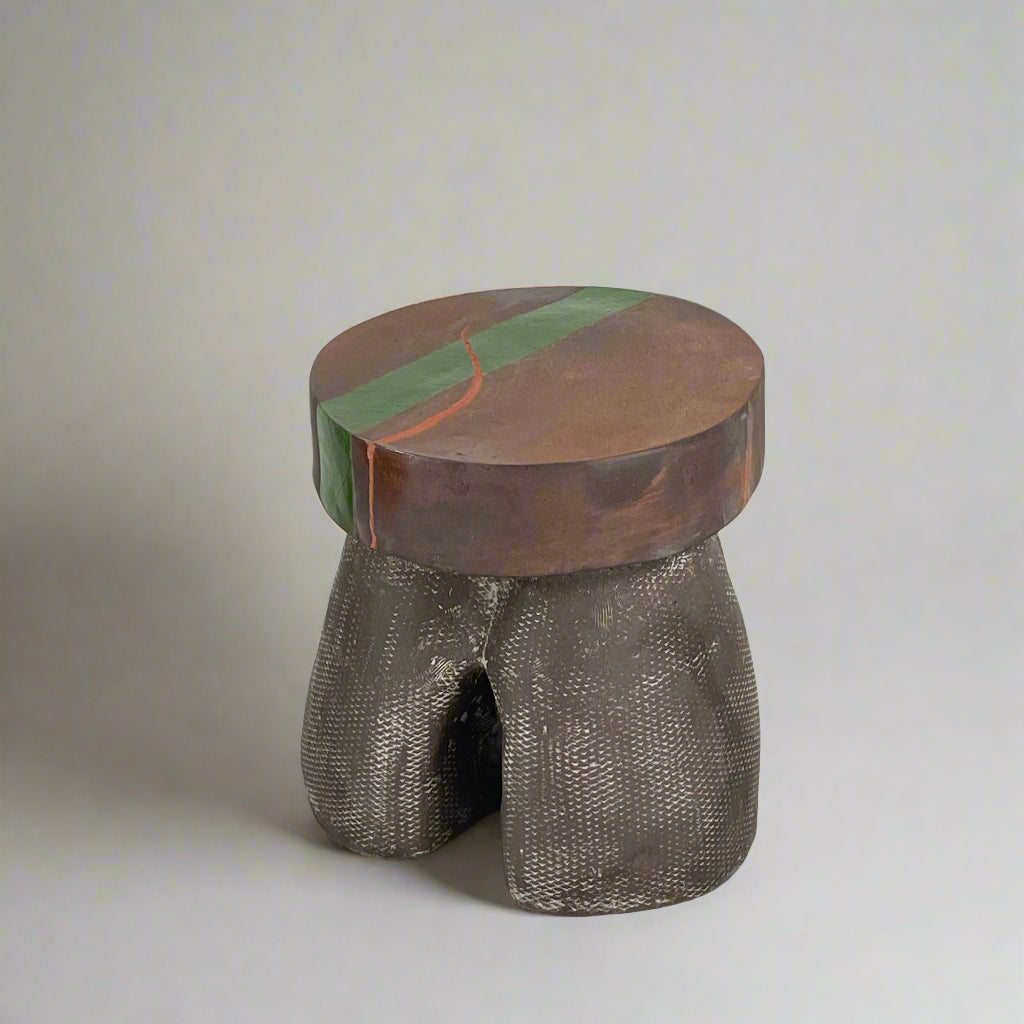 The Allyn Davis Mrs Beastie Ceramic Side Table by Artist features a round, textured design with a wooden top and green stripe. Its woven four-legged base subtly incorporates Kintsugo elements, adding depth and character to the piece.