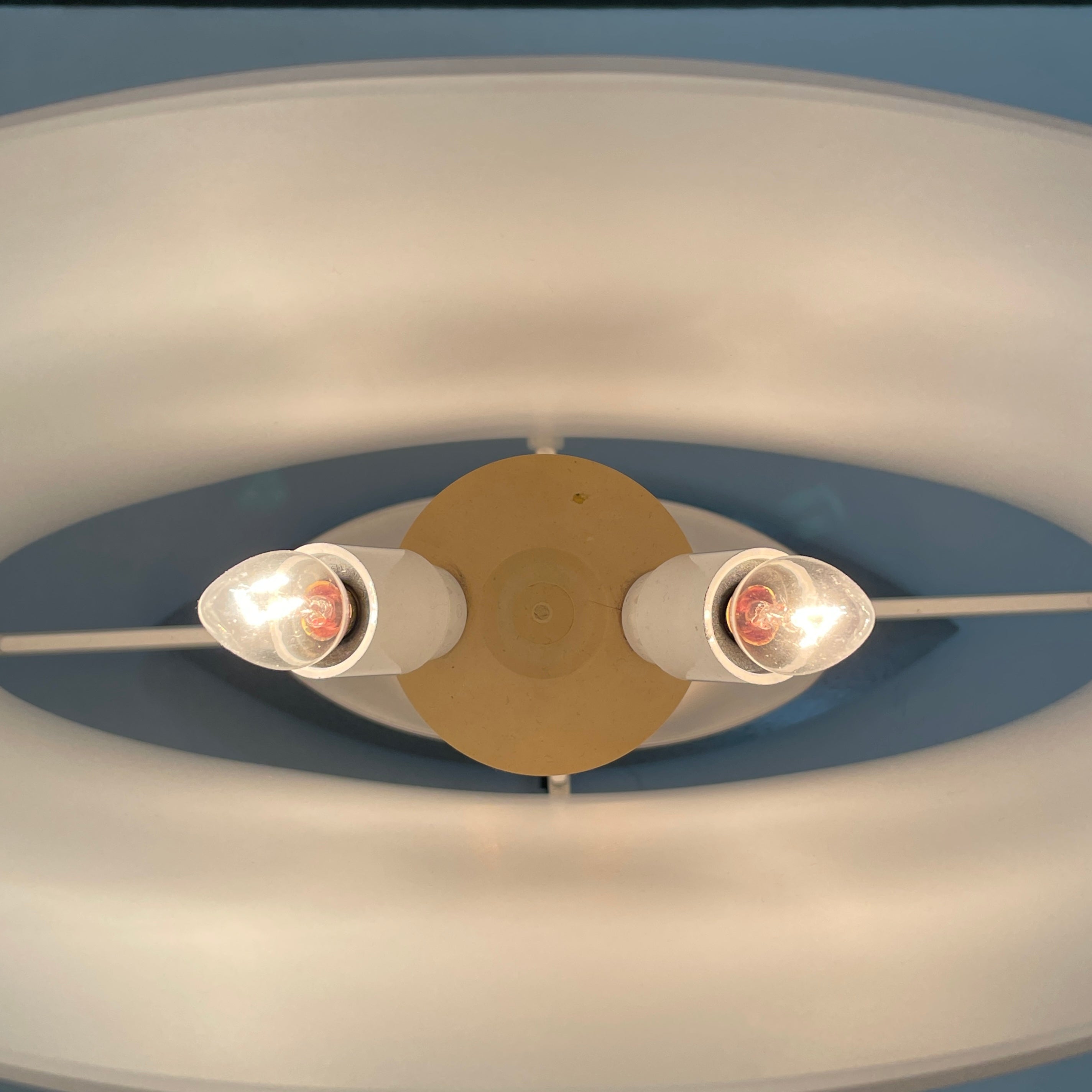 The Fontana Arte 3064 Table Light by Fontana Arte, echoing Daniela Puppa's designs, boasts a wide conical shade for a warm glow. It sits elegantly on a white surface against a plain backdrop, capturing the essence of postmodern art.