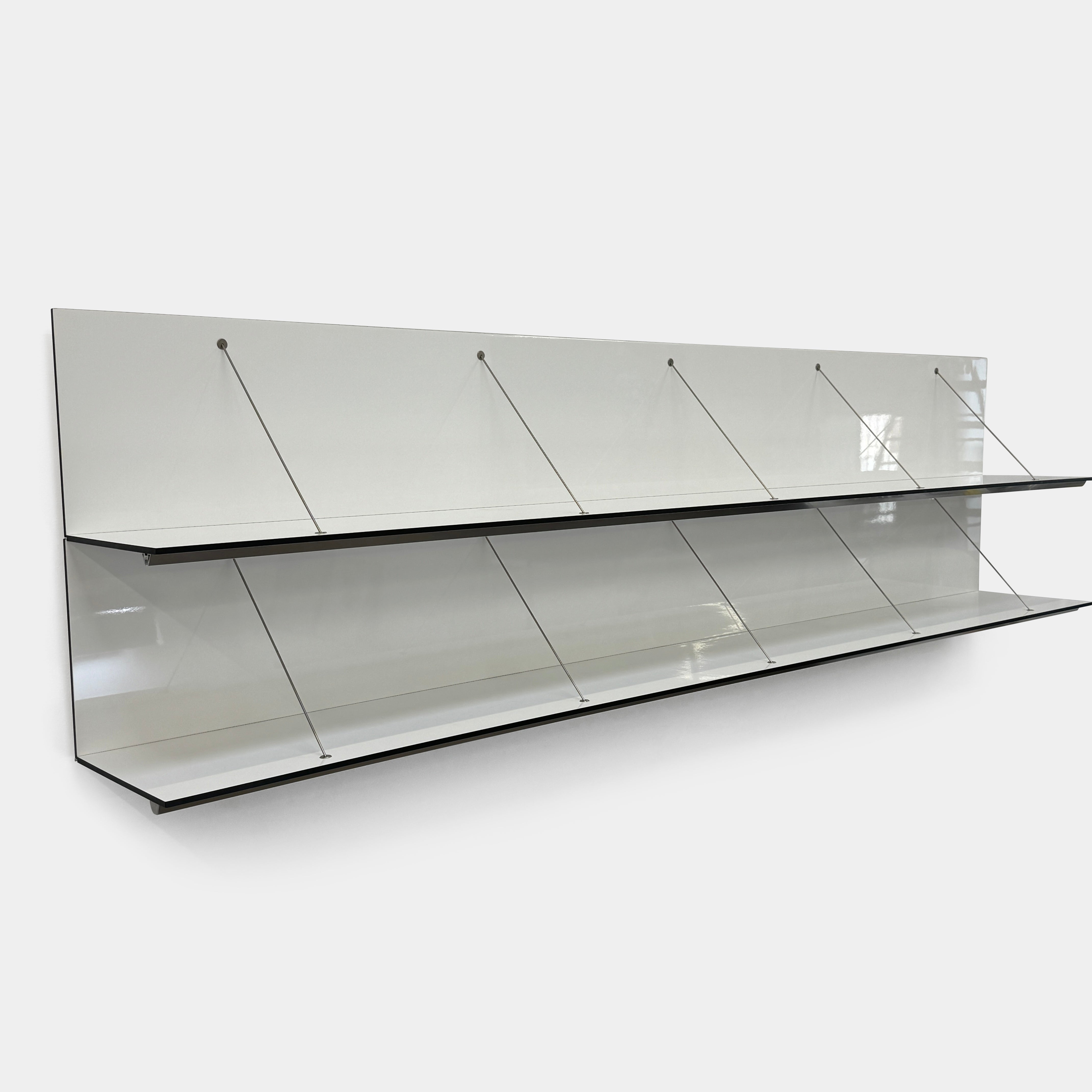 Two long, empty black shelves from the B&B Italia PAB Shelving collection are mounted on a white wall, supported by evenly spaced metal brackets.