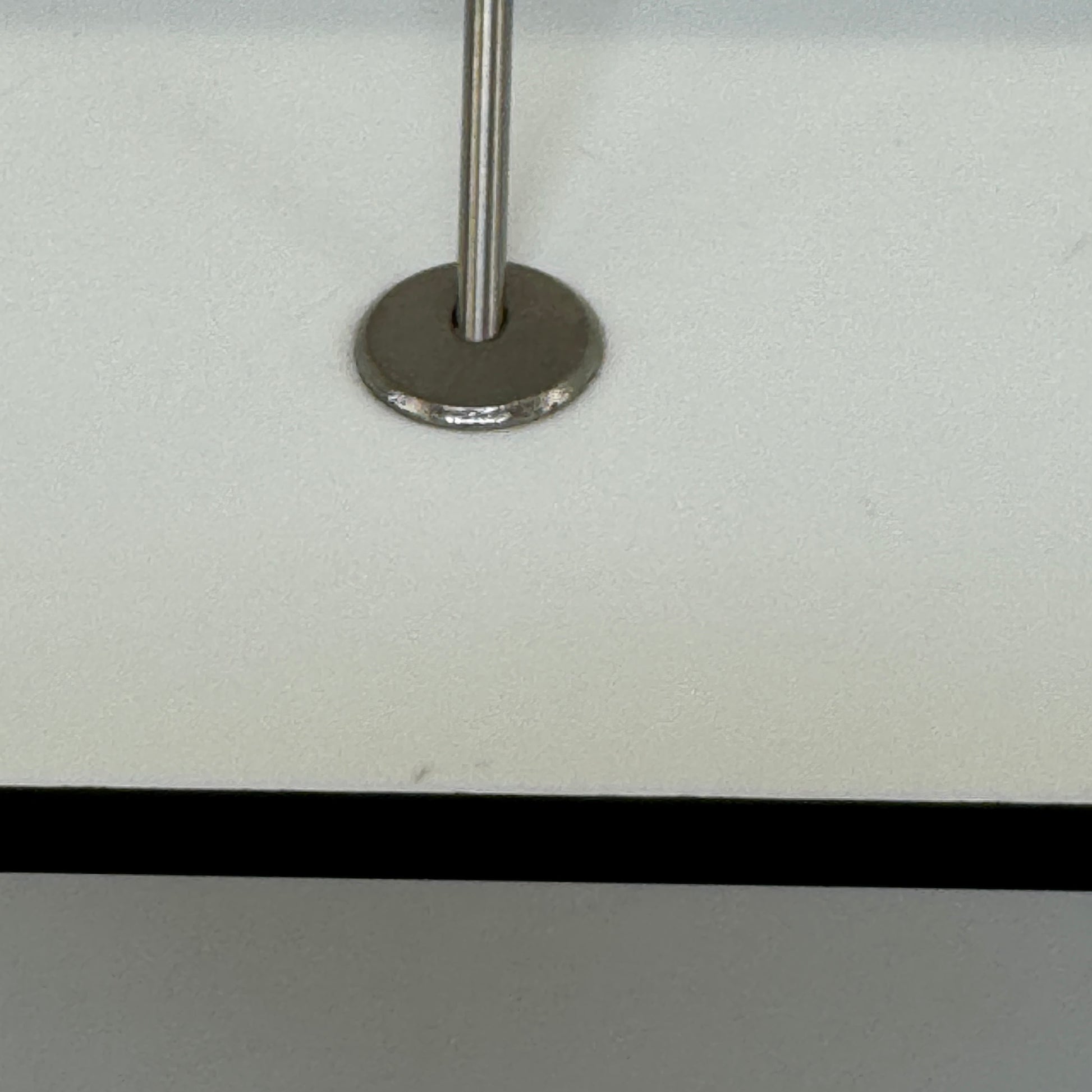 Two long, empty black shelves from the B&B Italia PAB Shelving collection are mounted on a white wall, supported by evenly spaced metal brackets.