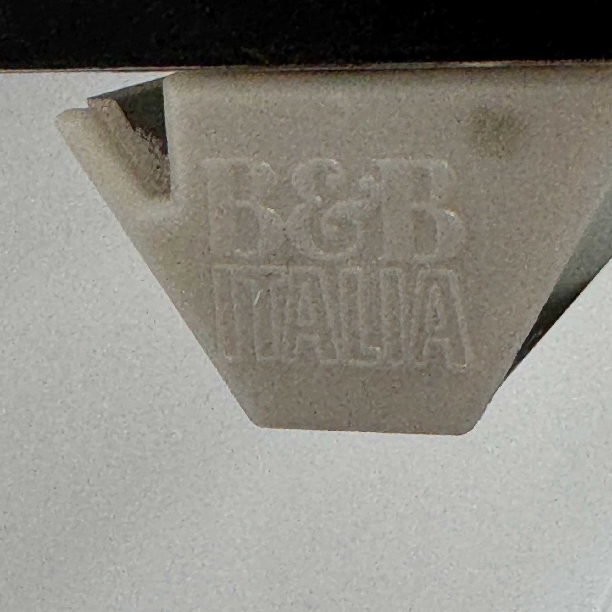 Two long, empty black shelves from the B&B Italia PAB Shelving collection are mounted on a white wall, supported by evenly spaced metal brackets.