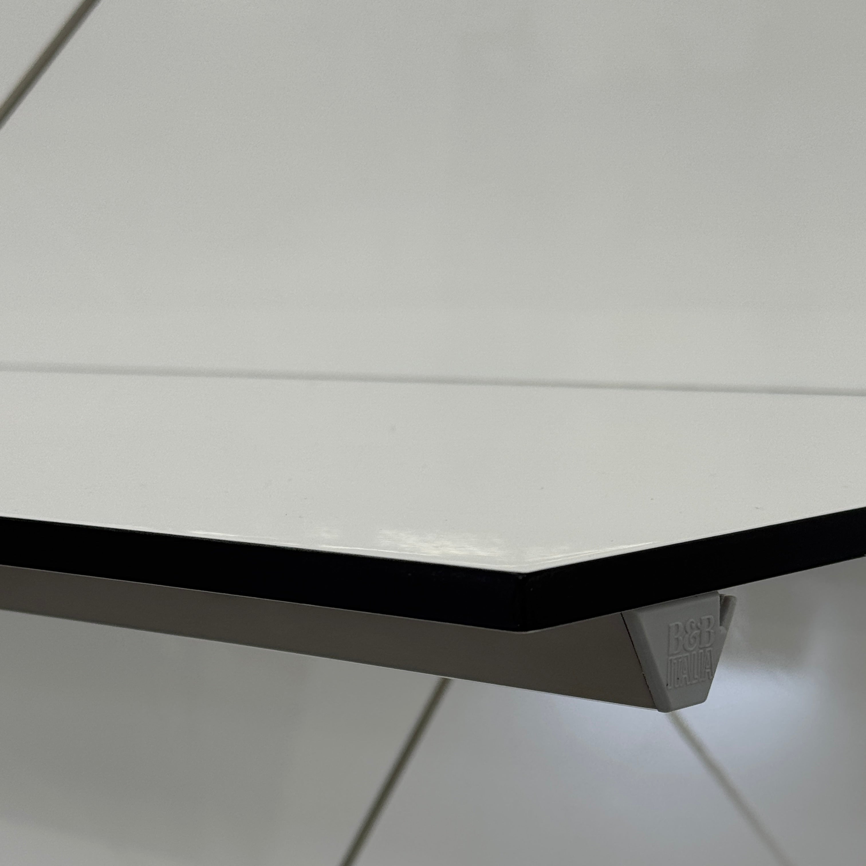 Two long, empty black shelves from the B&B Italia PAB Shelving collection are mounted on a white wall, supported by evenly spaced metal brackets.