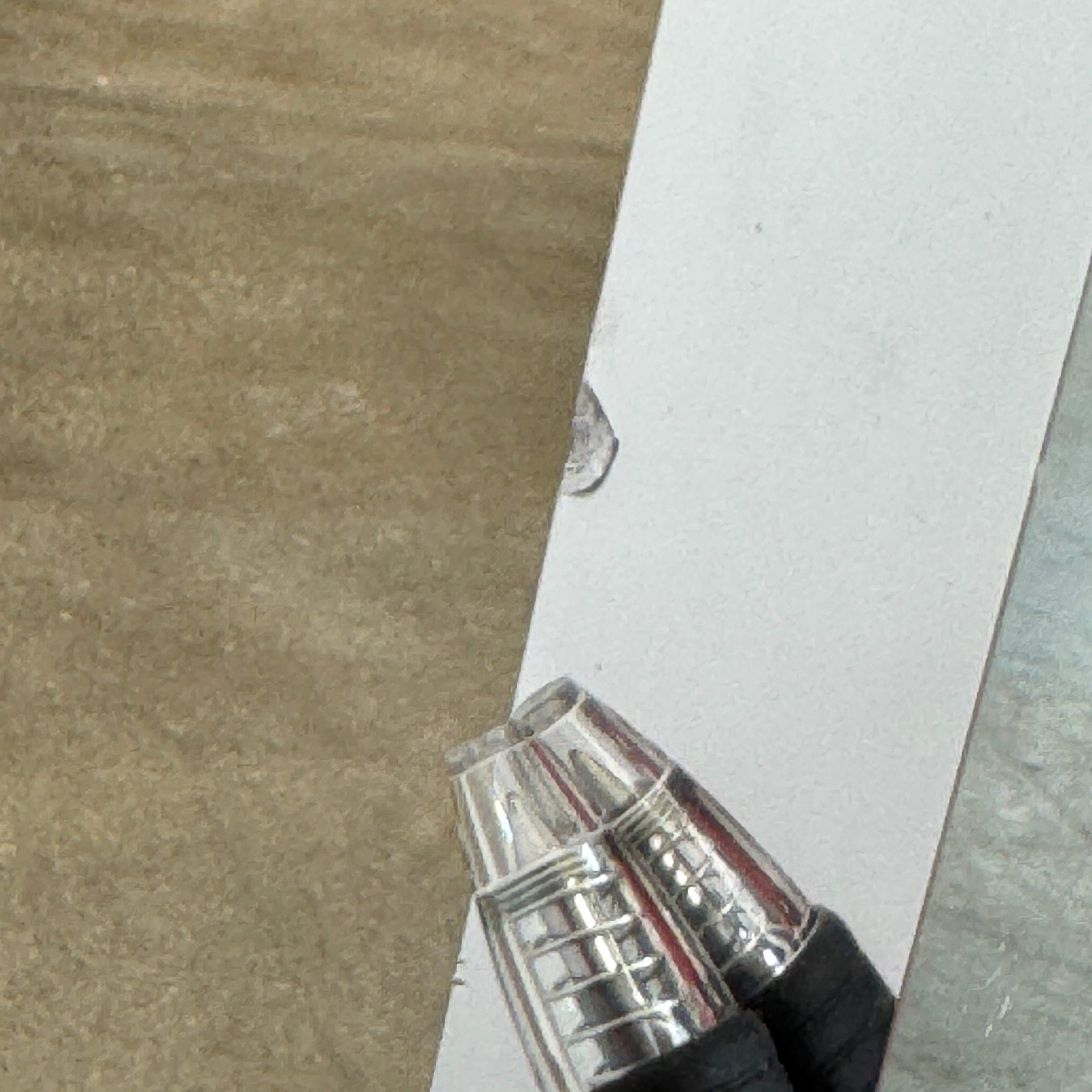 The Molteni & C Diamond table features a rectangular black marble top and angled polished metal legs, set on a brown concrete floor against a plain white wall. This piece by Molteni & C adds sophisticated elegance to any space.