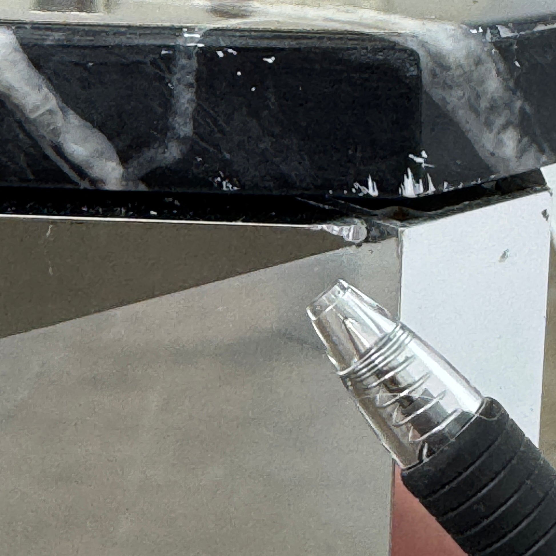 The Molteni & C Diamond table features a rectangular black marble top and angled polished metal legs, set on a brown concrete floor against a plain white wall. This piece by Molteni & C adds sophisticated elegance to any space.