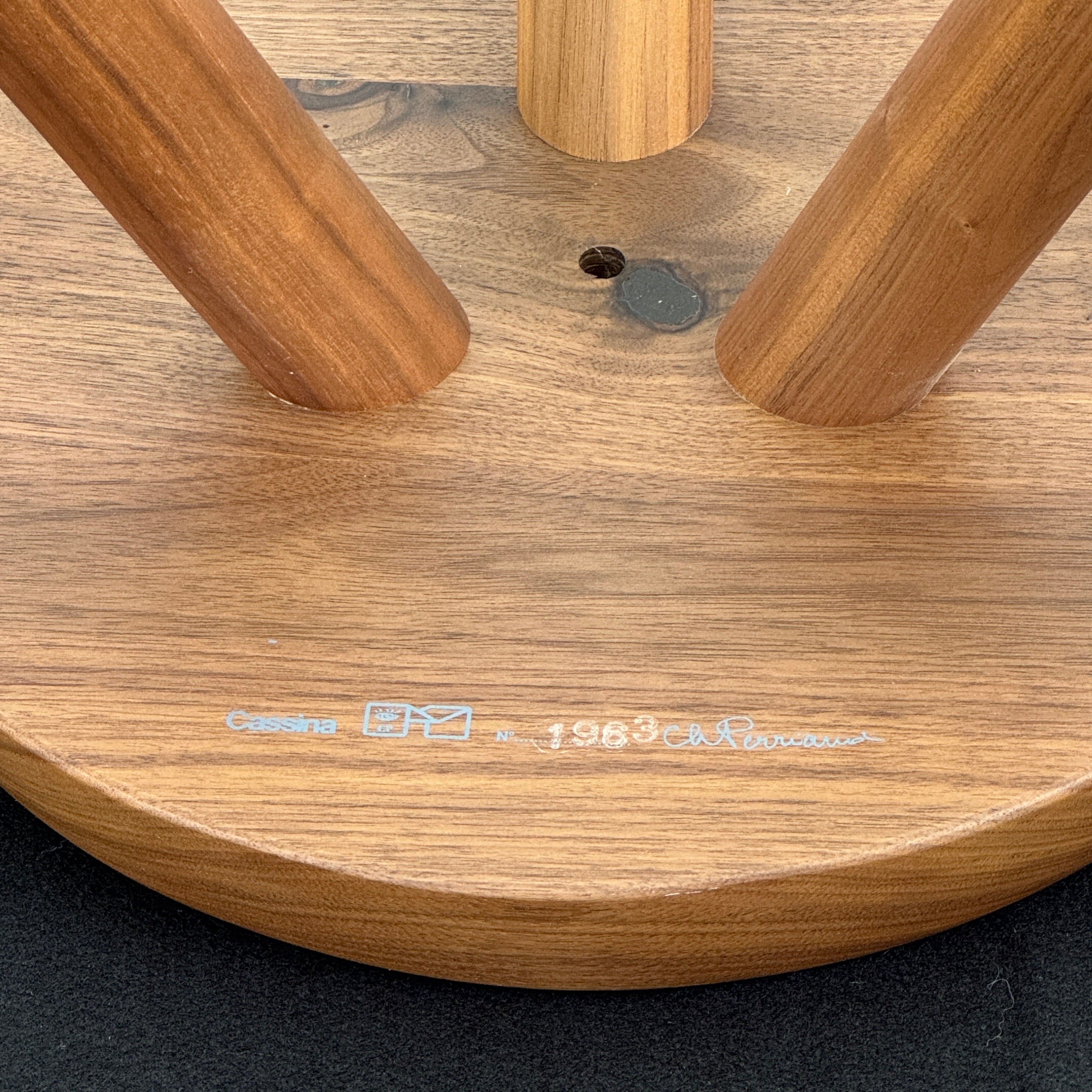 The Cassina “524 Tabouret Berger” stool by Cassina, crafted in walnut with three tapered legs and a round seat, is shown against a plain white background.