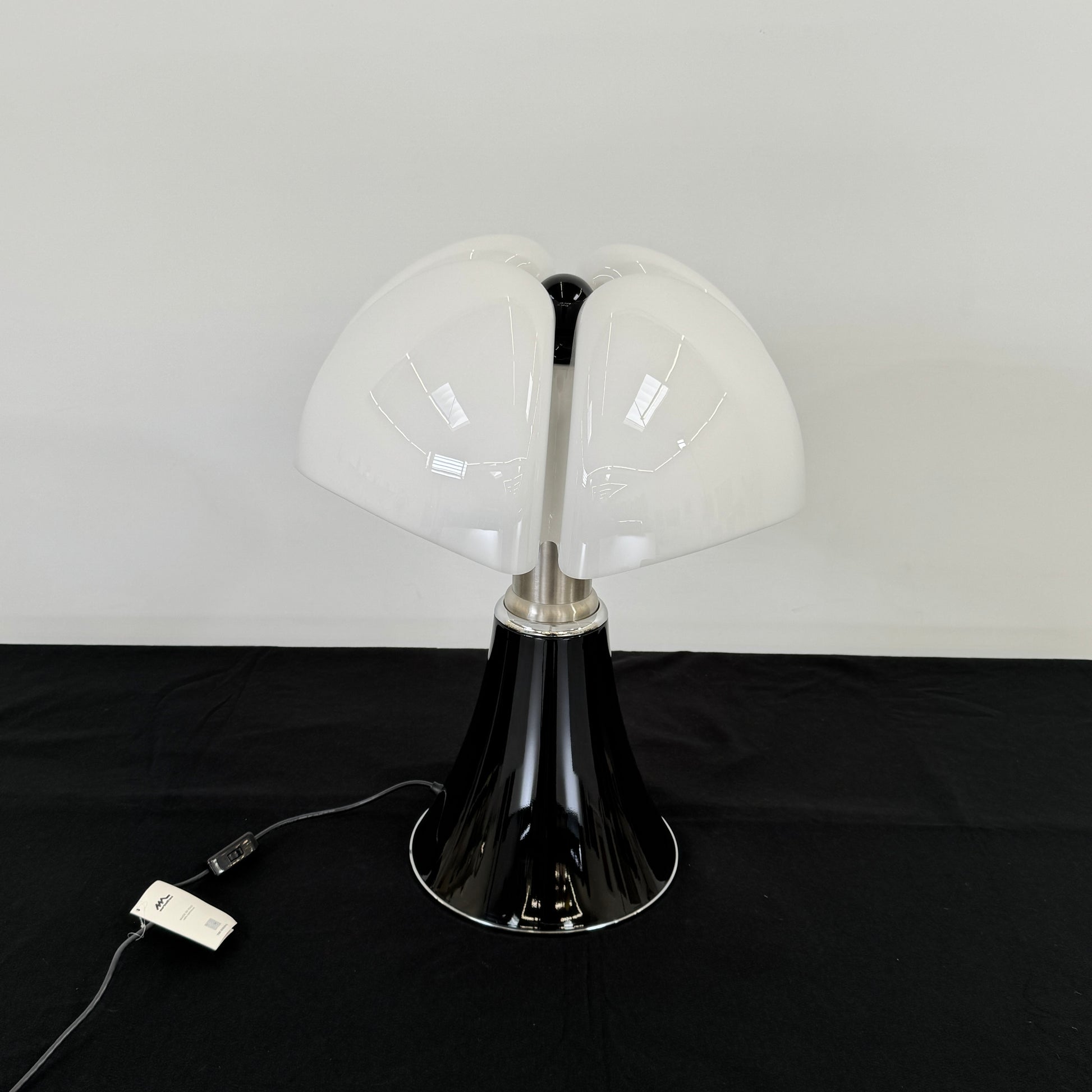 The Martinelli Luce Pipistrello Table Lamp by Martinelli Luce features a black base, silver neck, and white dome-shaped shade, shown against a plain white background with visible power cord and tag.
