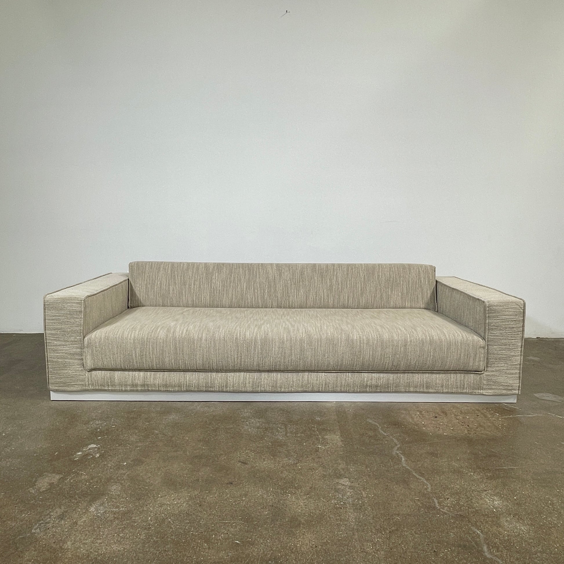 The Tacchini Low Sofa with Convertible Backrest by Tacchini showcases a sleek gray design, clean lines, and rectangular arms, all elegantly set against a crisp white background.