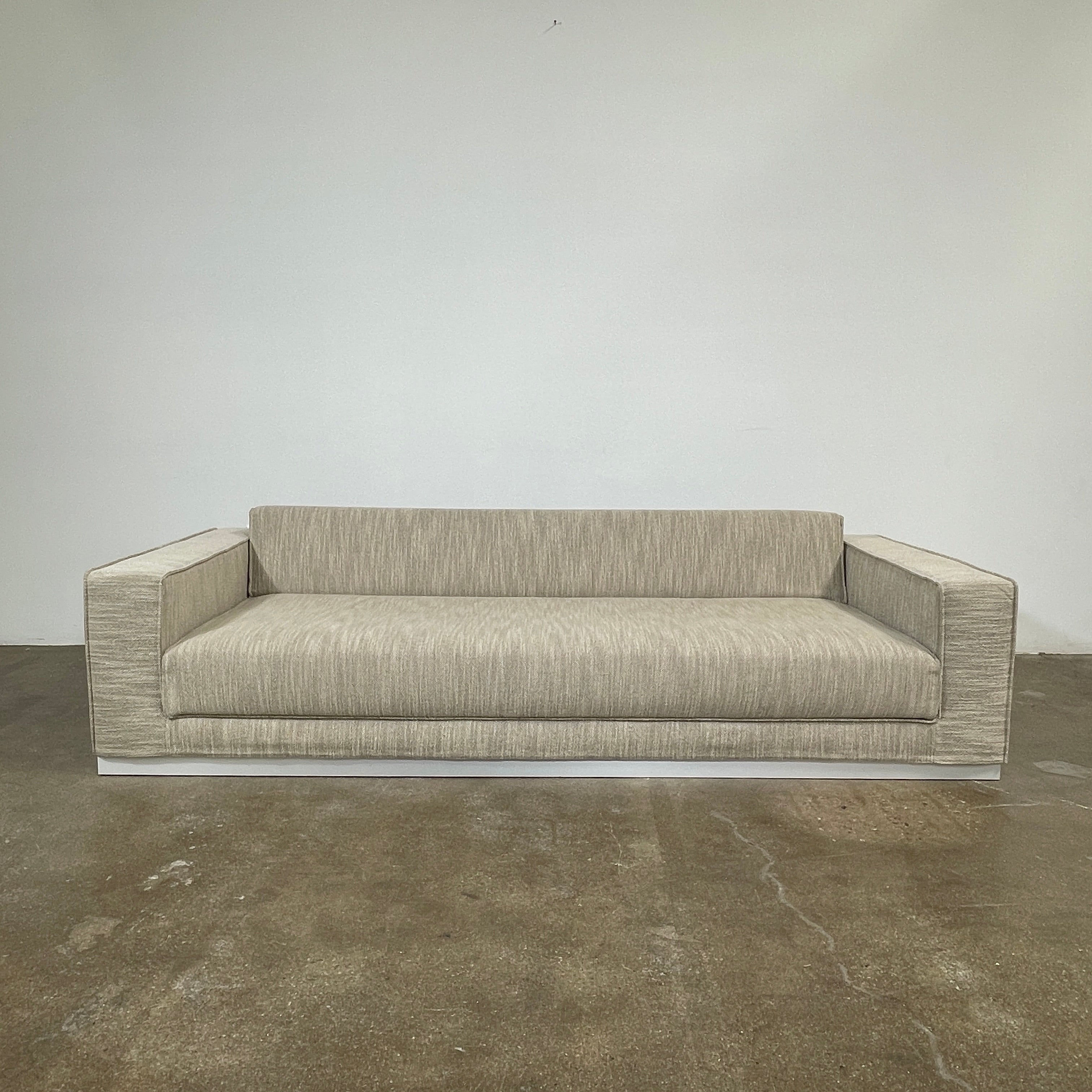 The Tacchini Low Sofa with Convertible Backrest by Tacchini showcases a sleek gray design, clean lines, and rectangular arms, all elegantly set against a crisp white background.