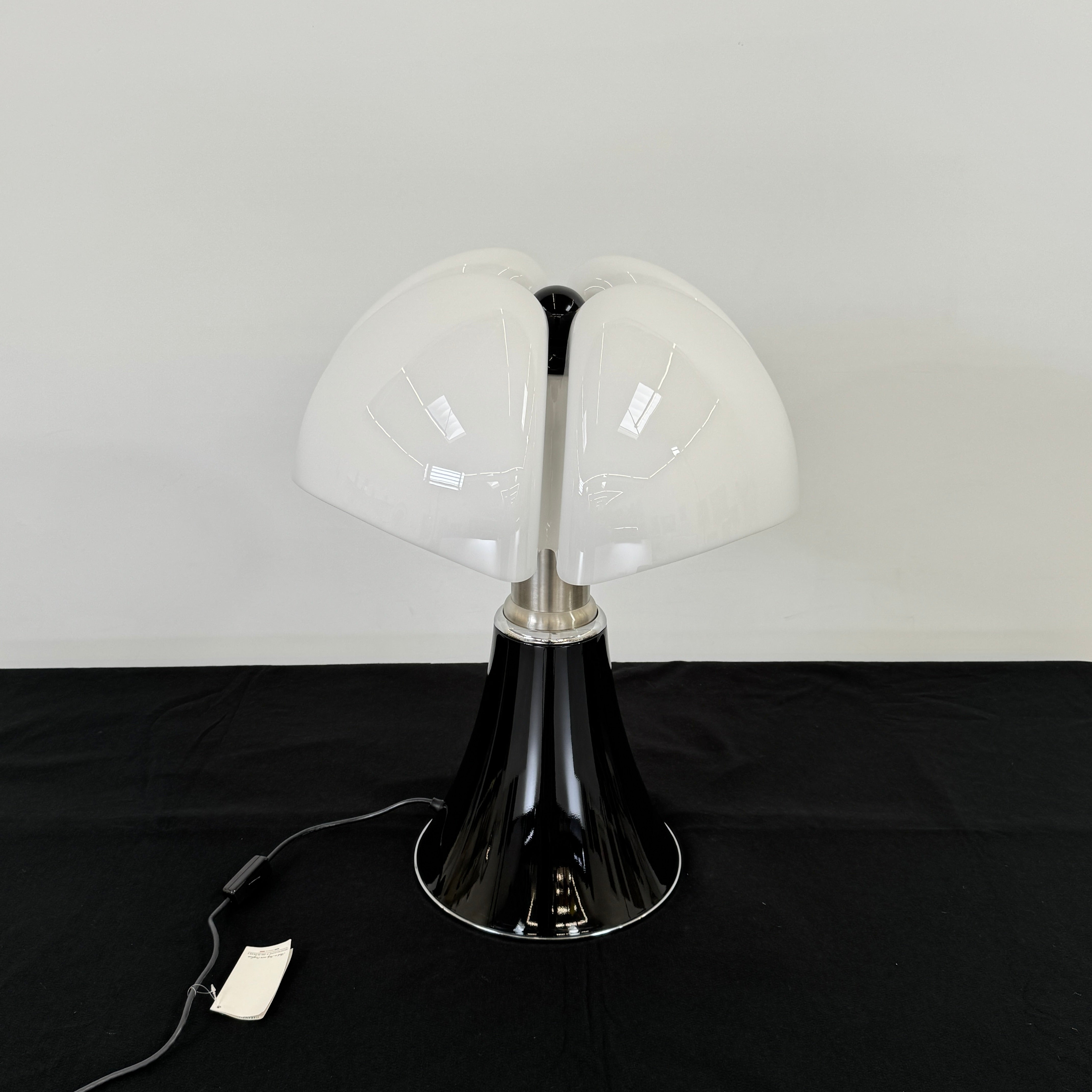The Martinelli Luce Pipistrello Table Lamp by Martinelli Luce features a black base, silver neck, and white dome-shaped shade, shown against a plain white background with visible power cord and tag.