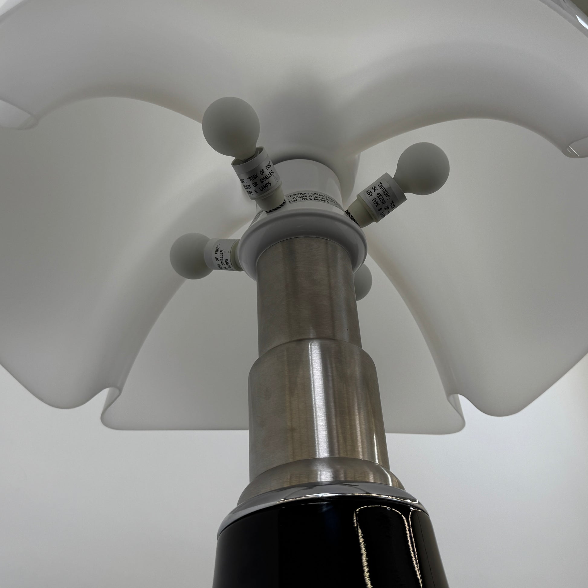 The Martinelli Luce Pipistrello Table Lamp by Martinelli Luce features a black base, silver neck, and white dome-shaped shade, shown against a plain white background with visible power cord and tag.