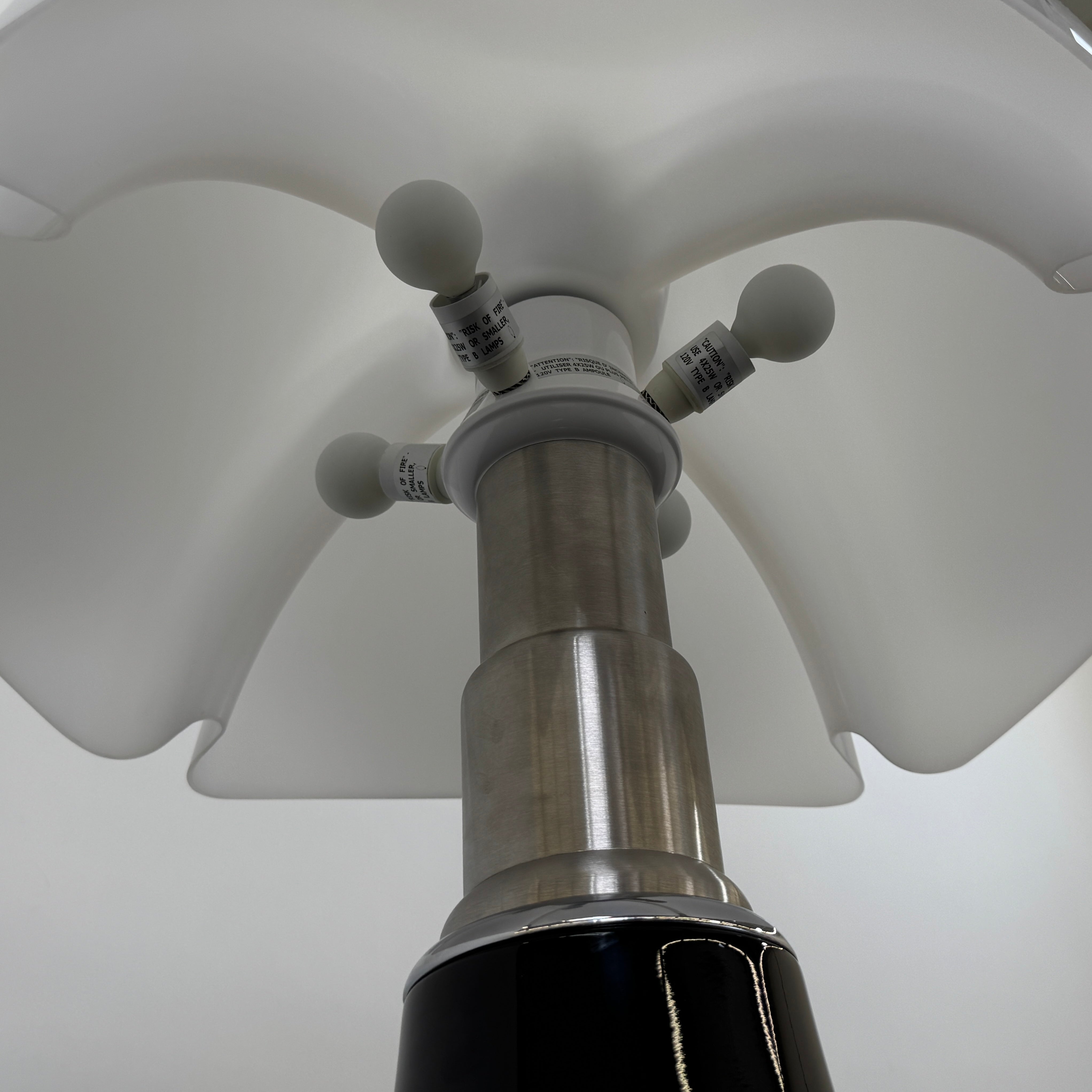 The Martinelli Luce Pipistrello Table Lamp by Martinelli Luce features a black base, silver neck, and white dome-shaped shade, shown against a plain white background with visible power cord and tag.