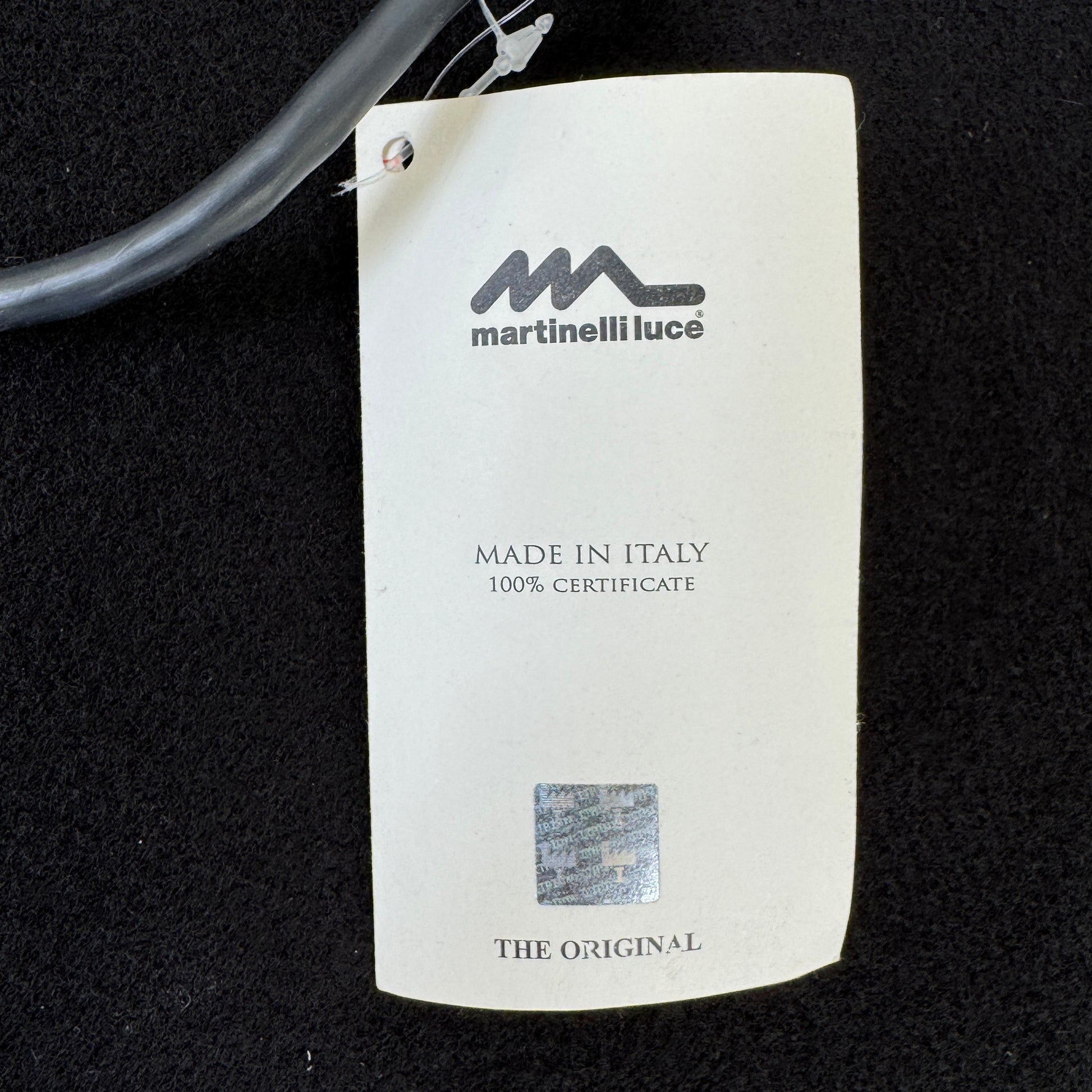 The Martinelli Luce Pipistrello Table Lamp by Martinelli Luce features a black base, silver neck, and white dome-shaped shade, shown against a plain white background with visible power cord and tag.