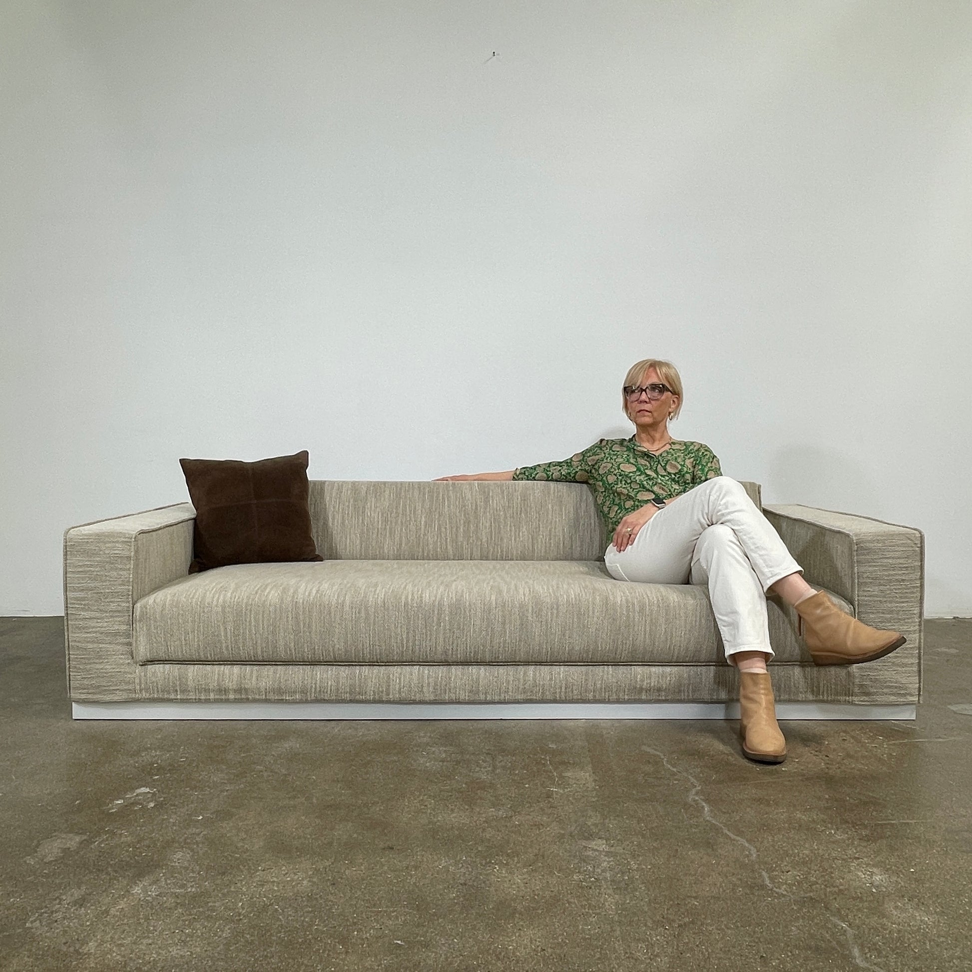 The Tacchini Low Sofa with Convertible Backrest by Tacchini showcases a sleek gray design, clean lines, and rectangular arms, all elegantly set against a crisp white background.