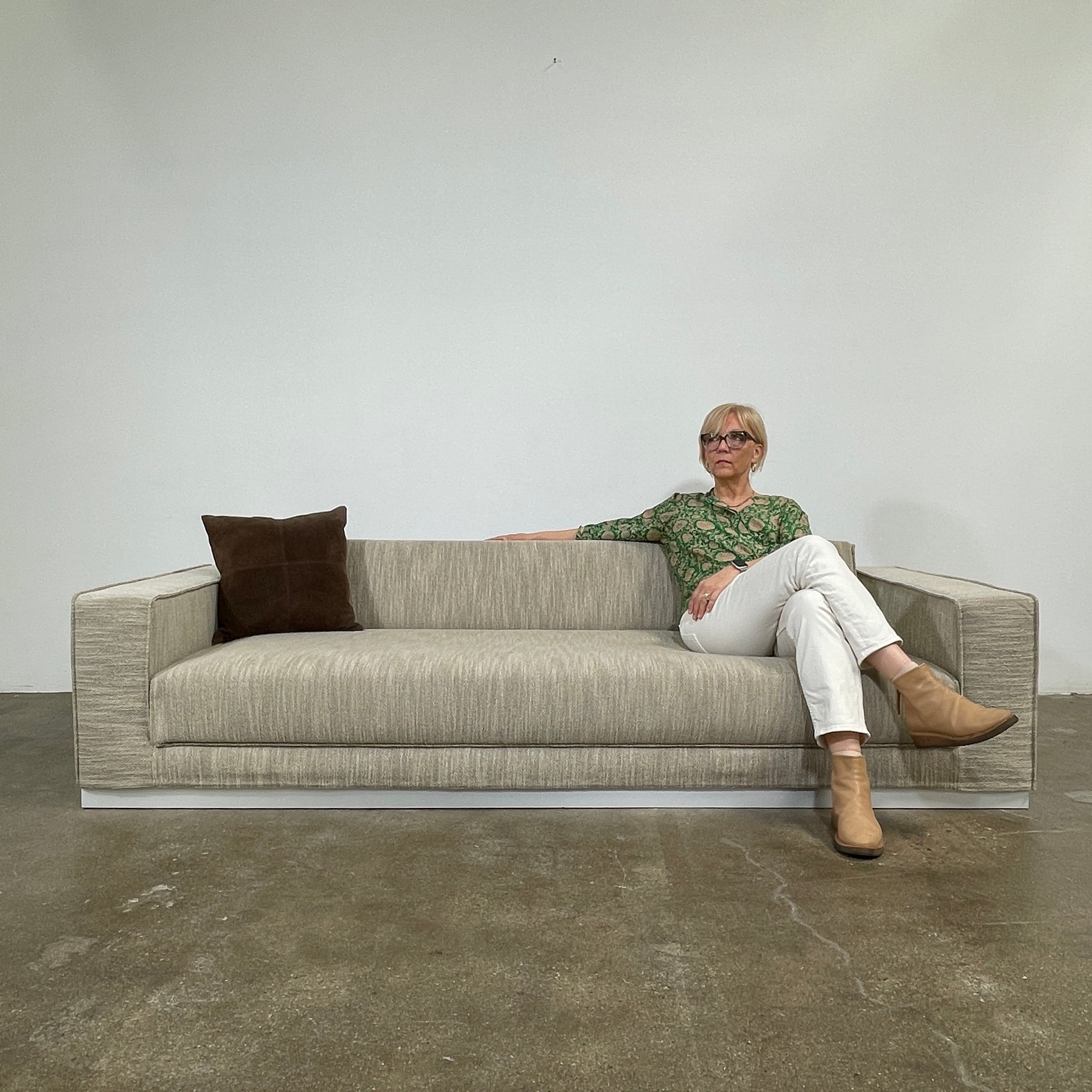 The Tacchini Low Sofa with Convertible Backrest by Tacchini showcases a sleek gray design, clean lines, and rectangular arms, all elegantly set against a crisp white background.