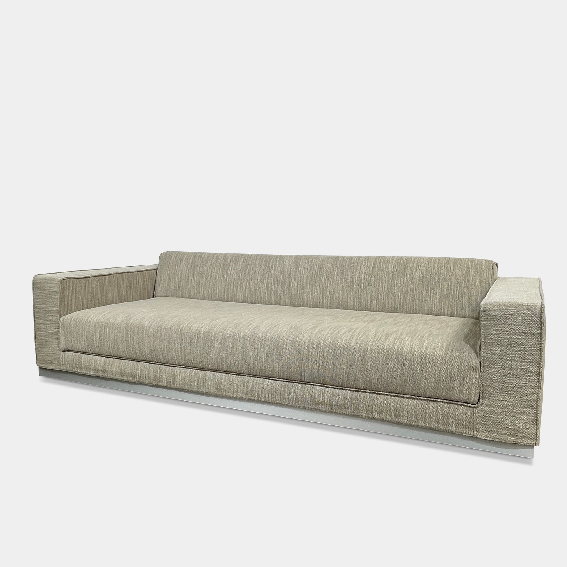 The Tacchini Low Sofa with Convertible Backrest by Tacchini showcases a sleek gray design, clean lines, and rectangular arms, all elegantly set against a crisp white background.