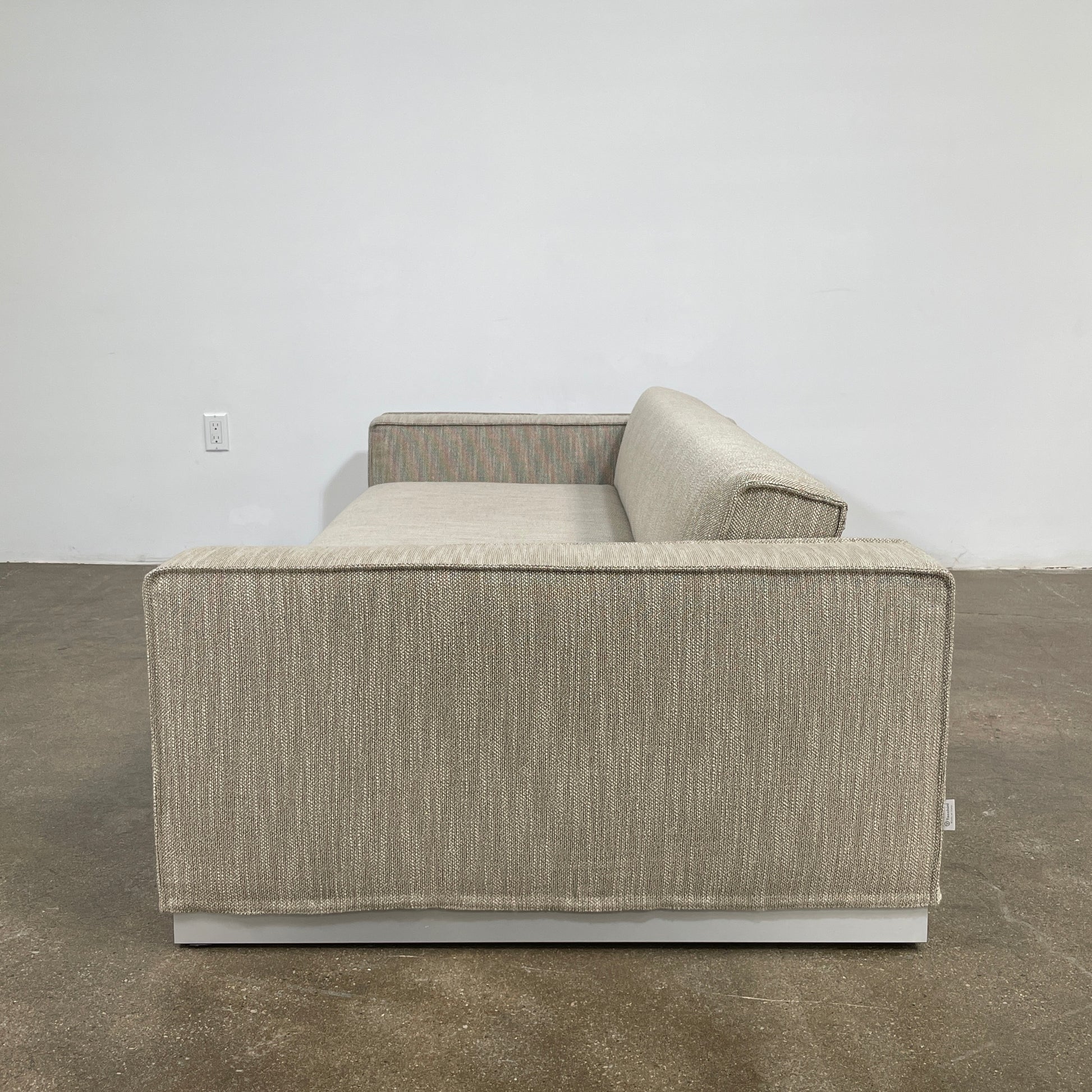 The Tacchini Low Sofa with Convertible Backrest by Tacchini showcases a sleek gray design, clean lines, and rectangular arms, all elegantly set against a crisp white background.
