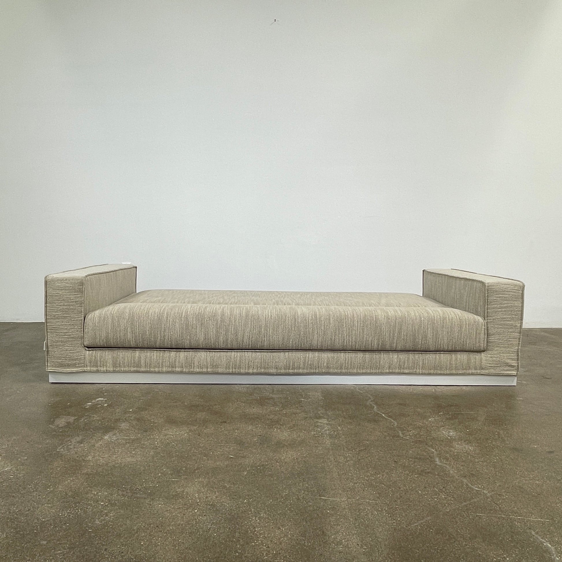 The Tacchini Low Sofa with Convertible Backrest by Tacchini showcases a sleek gray design, clean lines, and rectangular arms, all elegantly set against a crisp white background.