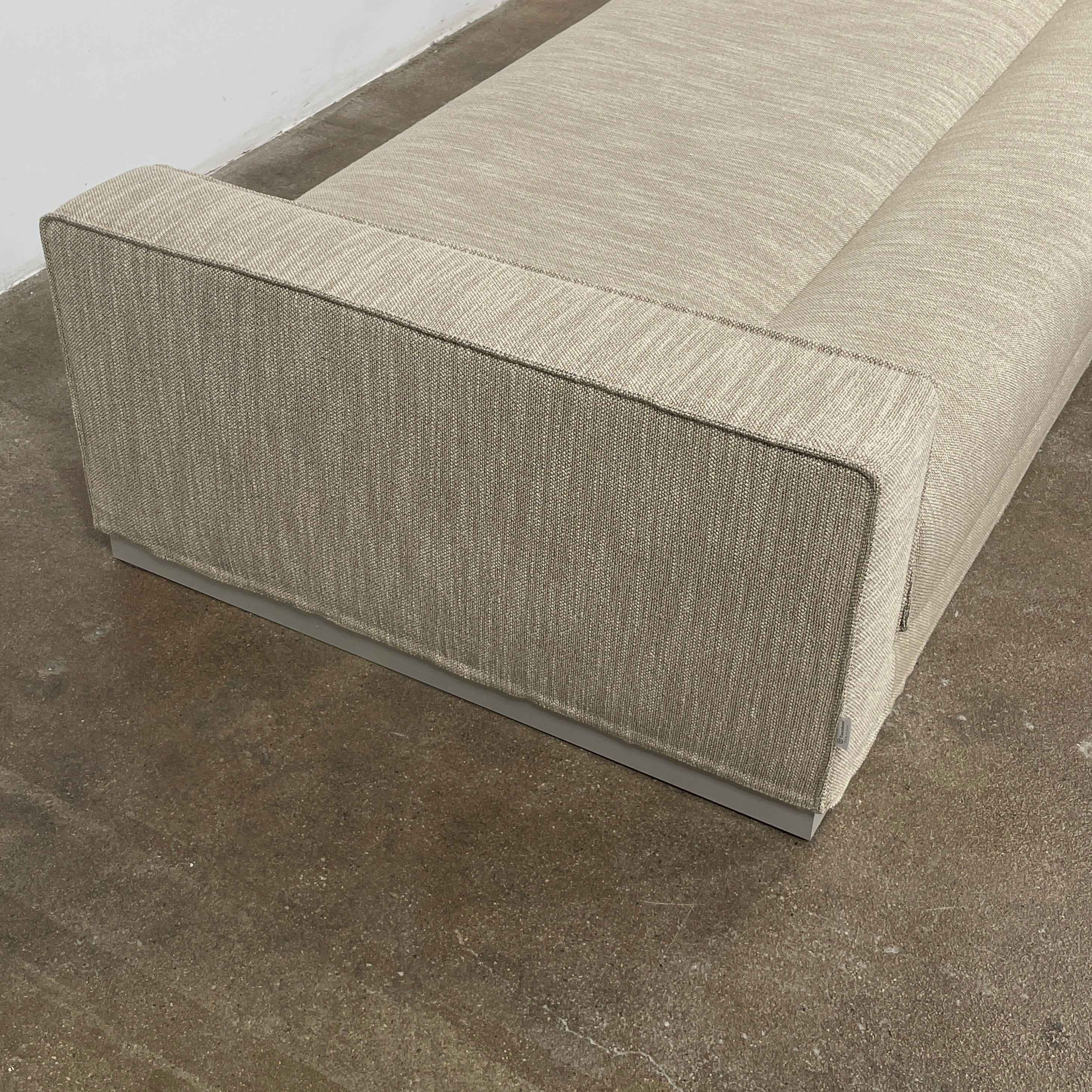 The Tacchini Low Sofa with Convertible Backrest by Tacchini showcases a sleek gray design, clean lines, and rectangular arms, all elegantly set against a crisp white background.