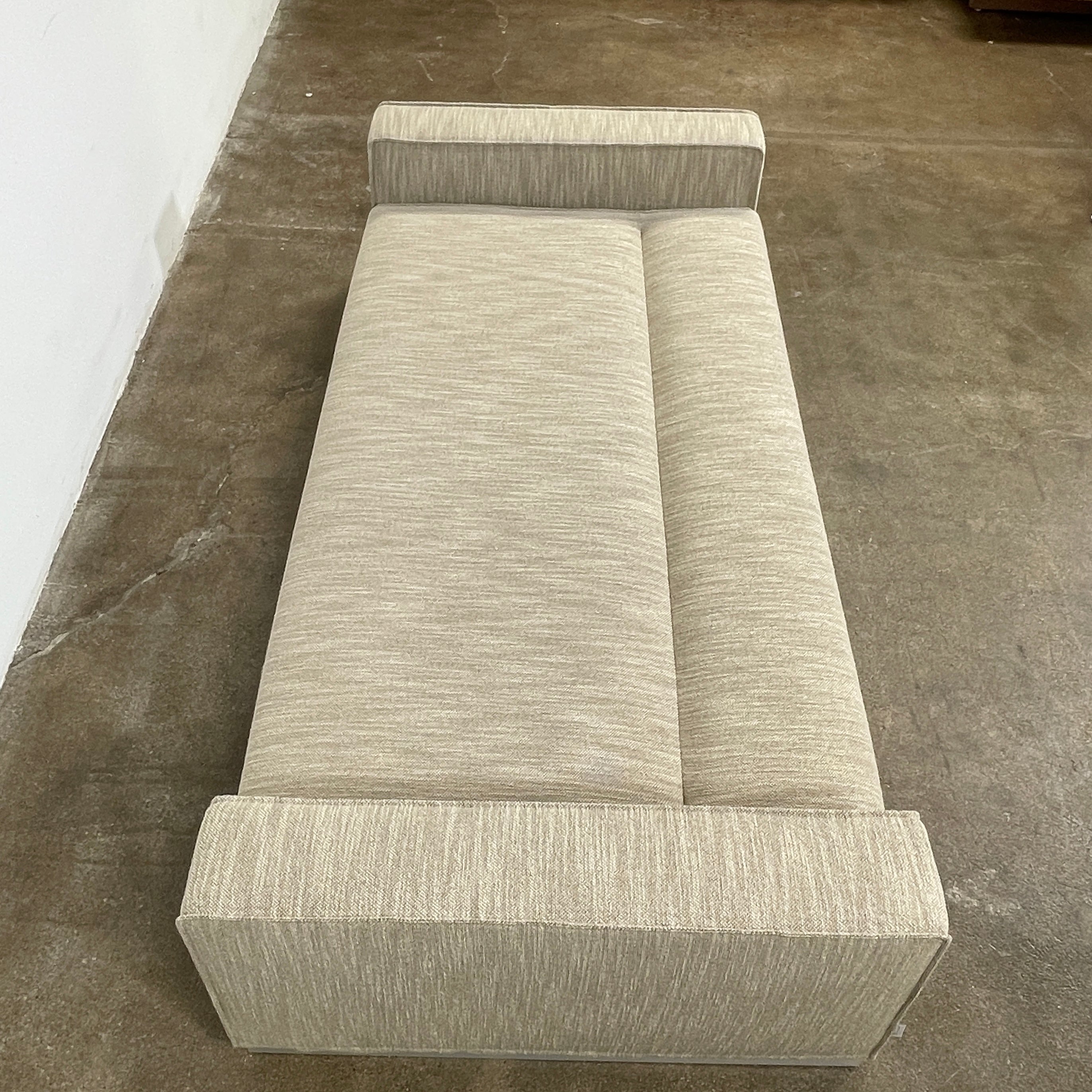 The Tacchini Low Sofa with Convertible Backrest by Tacchini showcases a sleek gray design, clean lines, and rectangular arms, all elegantly set against a crisp white background.