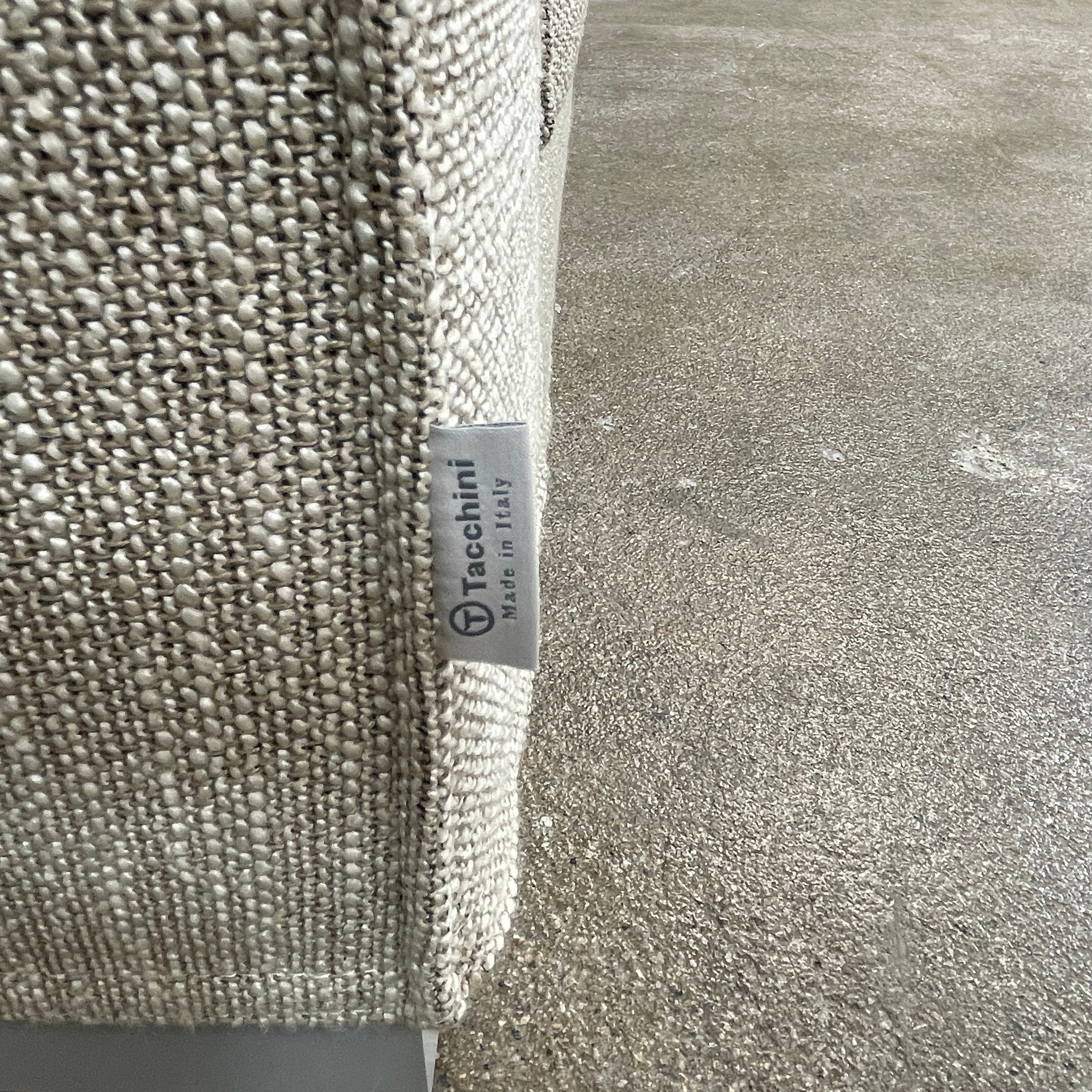 The Tacchini Low Sofa with Convertible Backrest by Tacchini showcases a sleek gray design, clean lines, and rectangular arms, all elegantly set against a crisp white background.